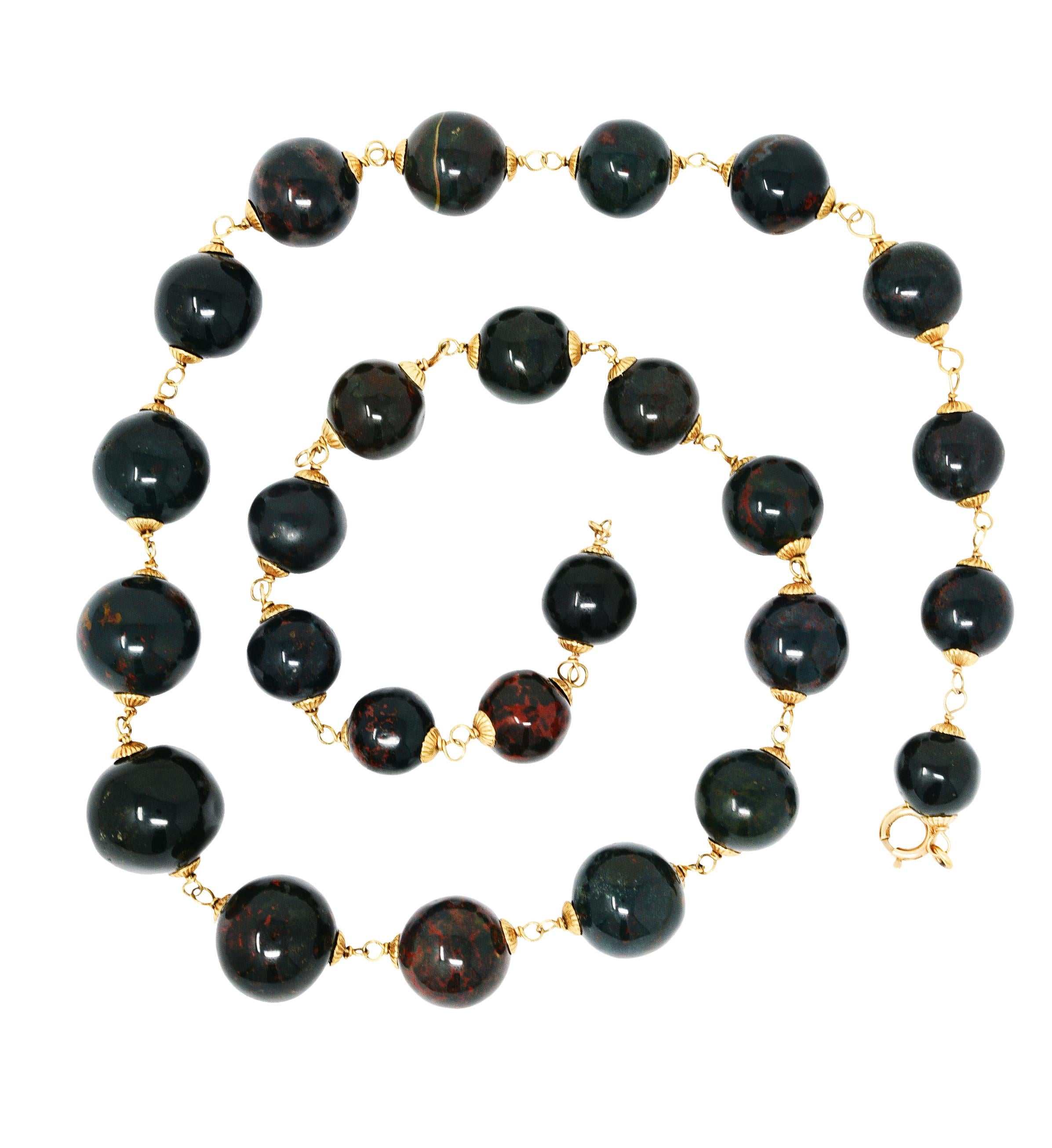 Necklace is comprised of round bloodstone beads measuring from 18.5 mm to 12.5 mm - graduated in size

Opaque bluish green to medium dark green with mild to strong red/orange mottling

Pigtailed in a strand via ribbed gold end caps flanking each