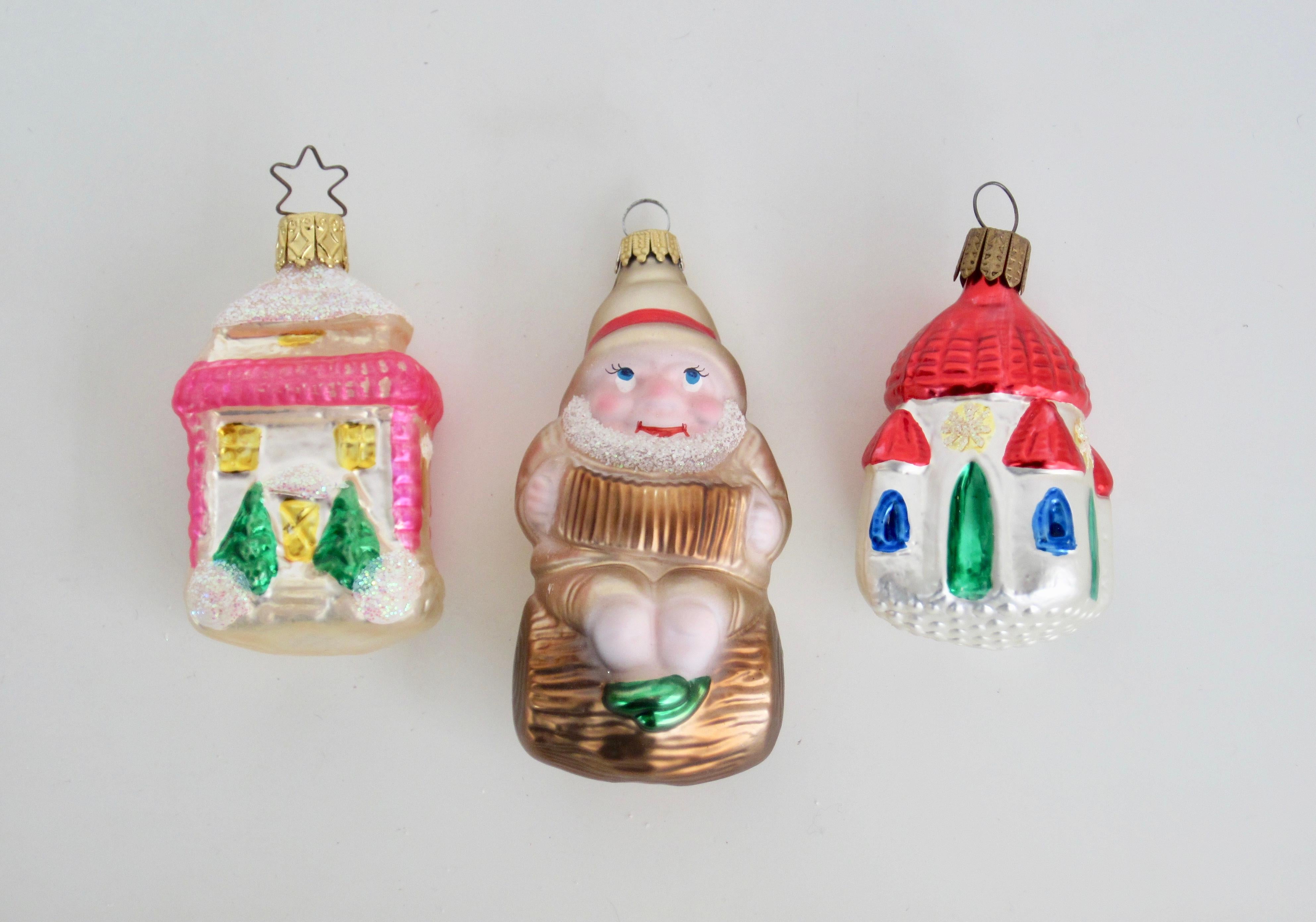 Set of three blown glass Christmas ornament including one charming gnome/dwarf and two houses. Colors are bright. Clean condition as expected for the age.

White, Pink, Gold House Dimensions: 1.25