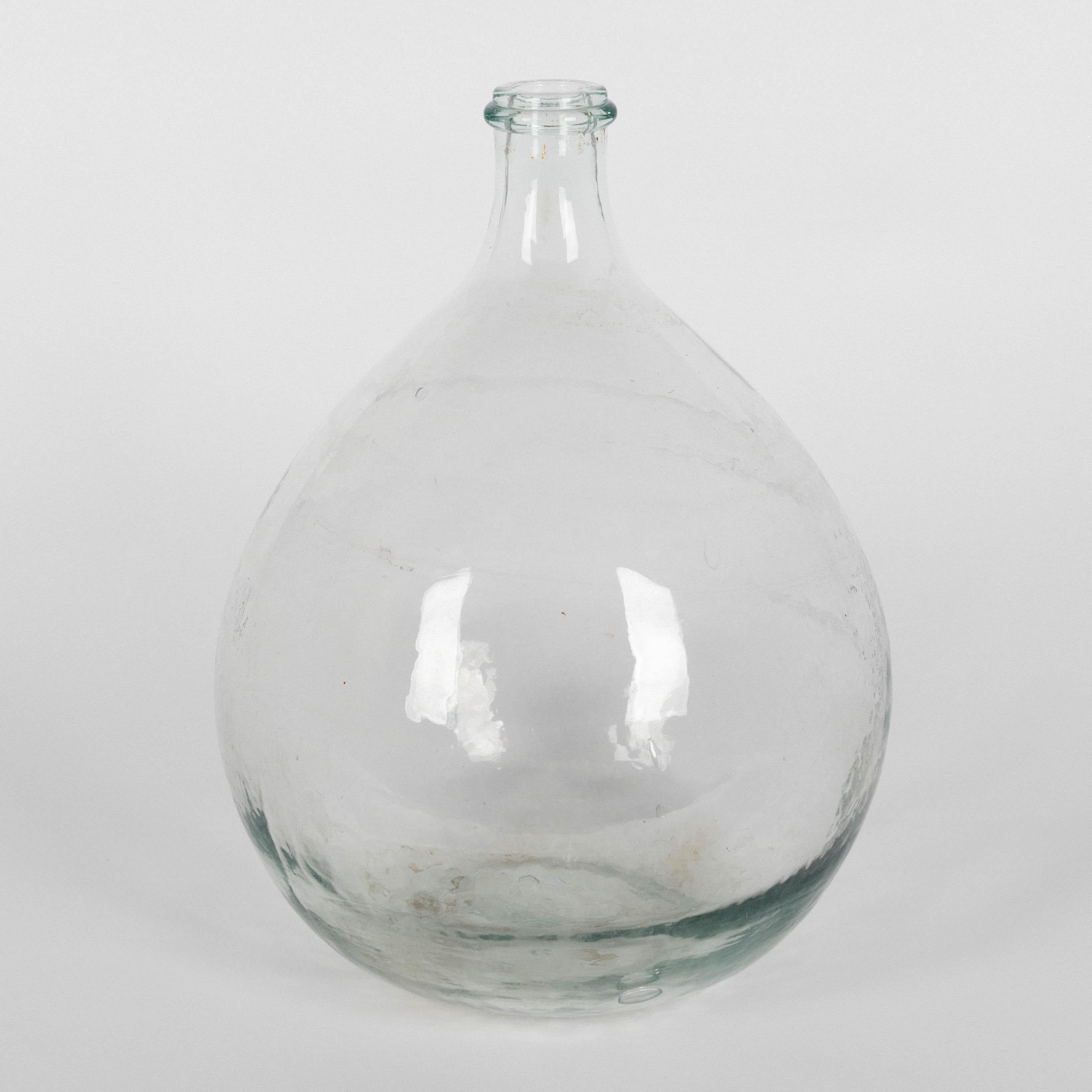 Un par de botellas de vidrio soplado a mano de forma globular, tipo dame Jeanne o damajuana. La botella transparente es probablemente francesa y la botella de agua es española, marcada V. Levante. Elementos decorativos perfectos para una casa en la