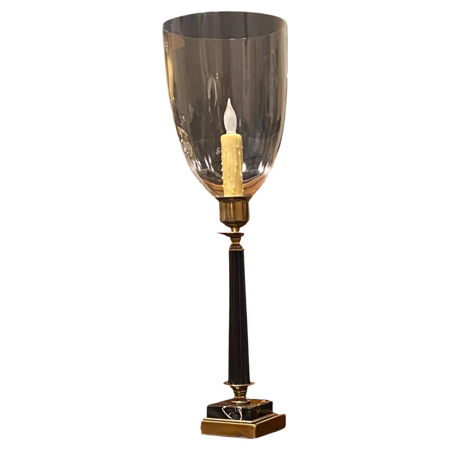 A neoclassical style hurricane lamp with a blown glass shade, polished brass, black fluted column and Belgian black marble candlestick base, now electrified with a beeswax candle sleeve. 
High style 1970’s at its best. 