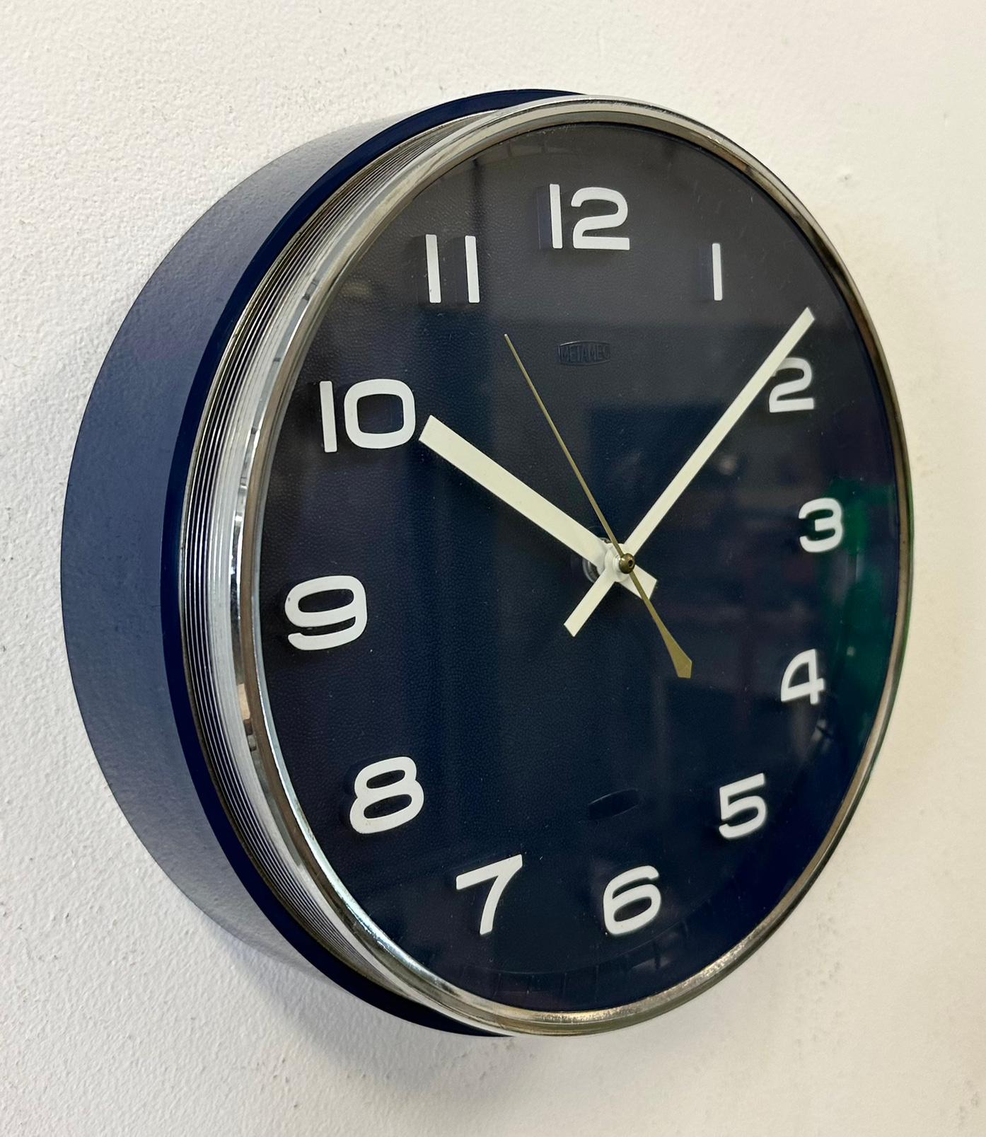 Metamec wall clock was made in United Kingdom during the 1970s. It features a blue bakelite body with chrome ring, an aluminium hands and a clear glass cover. Original electric movement ( 220 V ) works perfectly . The diameter of the clock is 25