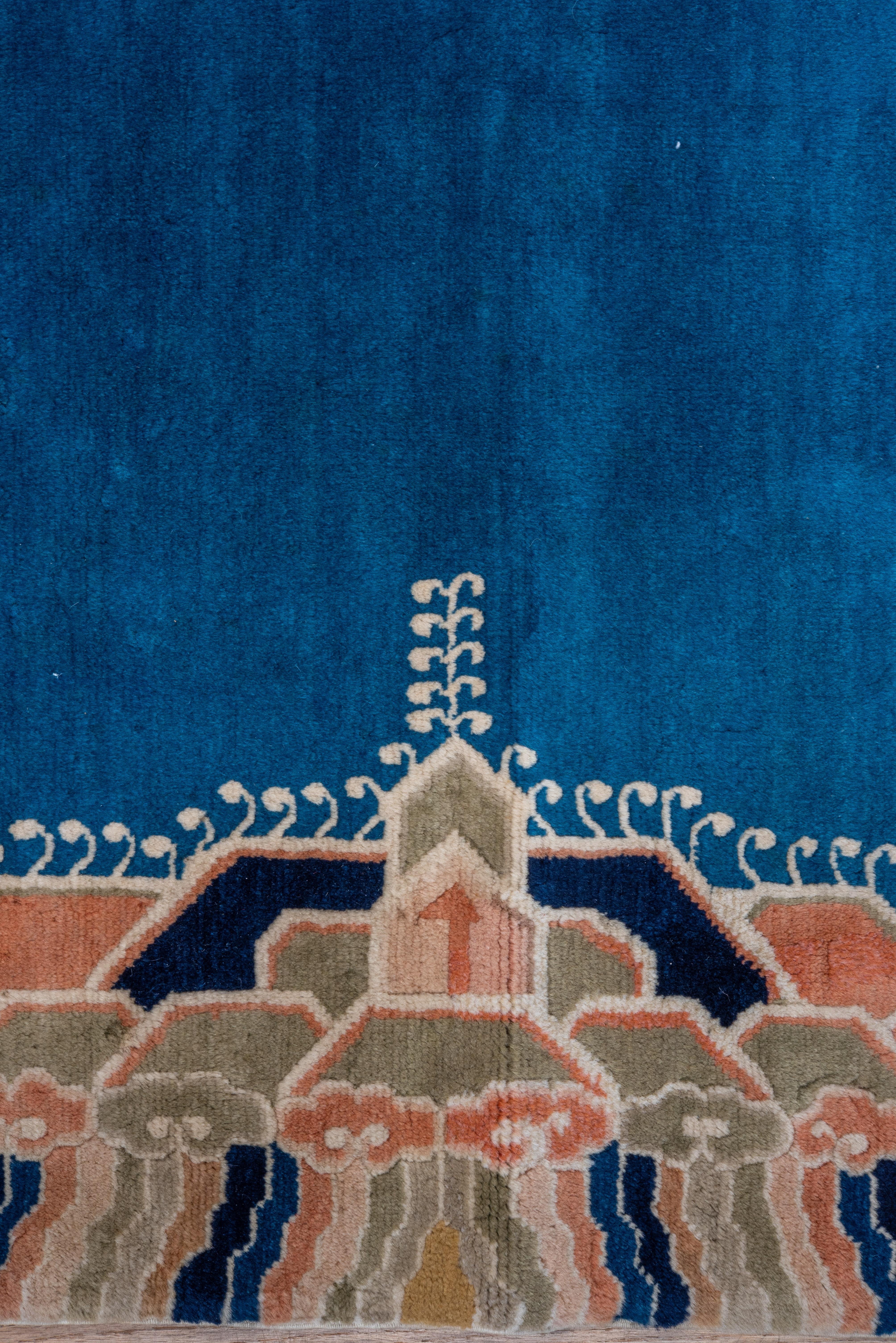 The cerulean blue field displays four writhing semi-profile scaly corner dragons and a matching central creature, full-face, above layered and pointed mountains at the cardinal points, and a surround in the polychrome Yun-tsao Tou style (clouds and