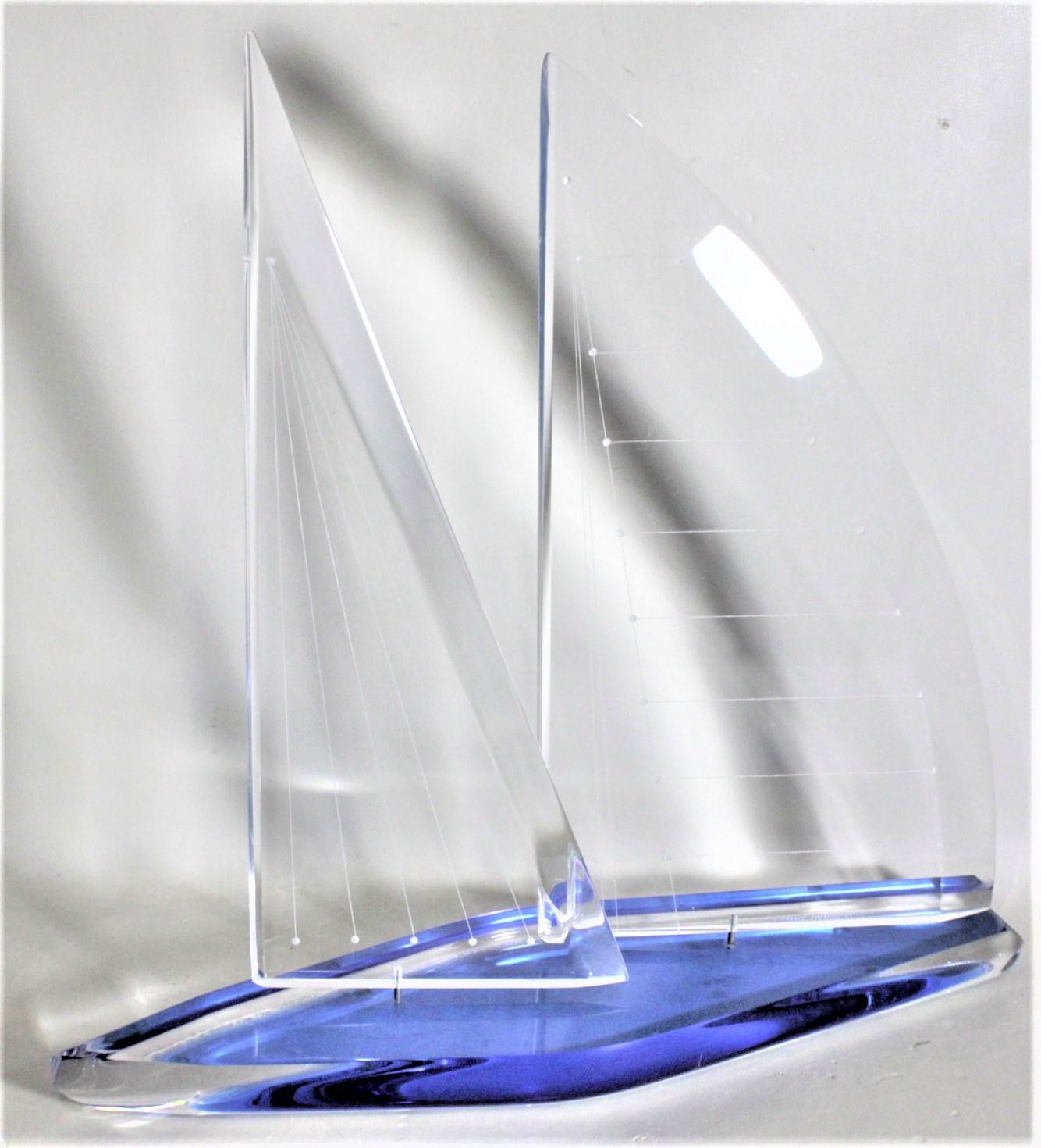This large solid lucite sailboat sculpture was made by Wintrade of Beverly Hills California in approximately 1980 in a Mid Century Modern style. The sculpture is done with clear lucite with a cobalt blue covering on the base, with aluminum brackets