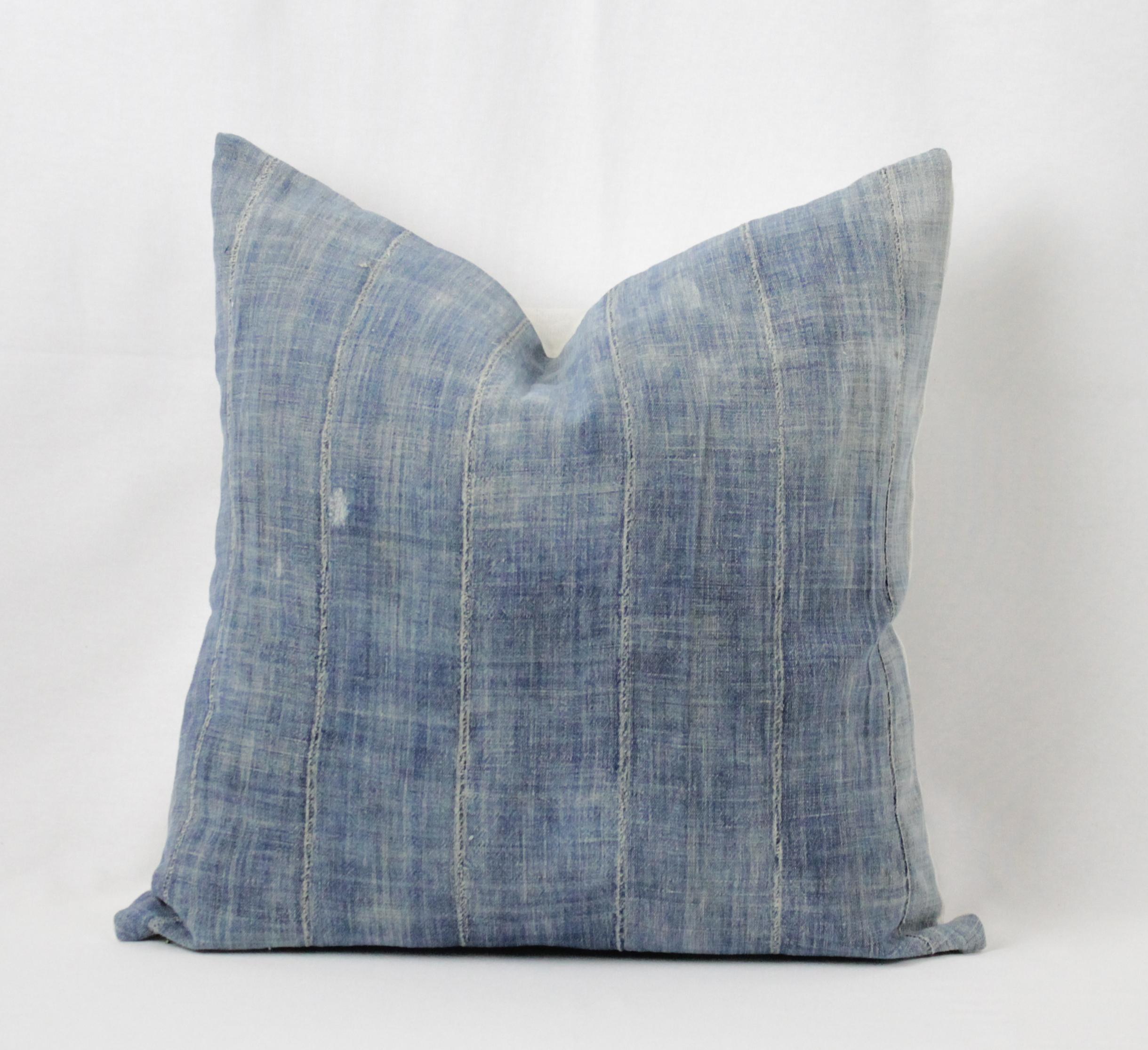 Blue distressed pillow with vertical seams, with zipper closure. Back is in a natural linen, finished with overlocked edges. Pillow has purposeful distressed areas, see pictures. Pillow is also lined with a natural linen. Main colors are blue. Does