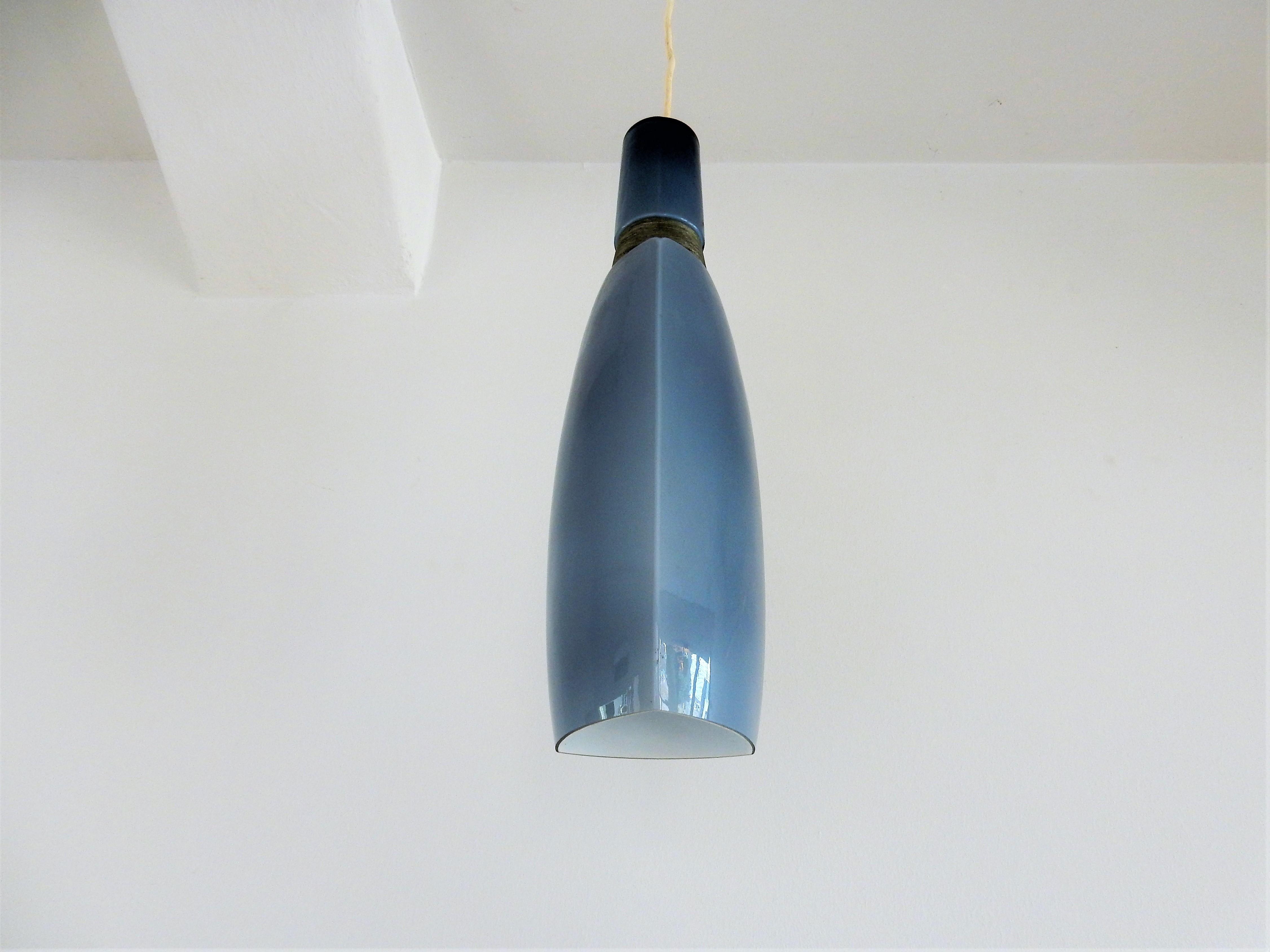 C'est une très belle lampe pendante vintage en verre bleu avec un détail en fil de métal. L'intérieur opalin donne une belle lumière douce. Ce luminaire est d'origine scandinave et souvent attribué à Holmegaard.