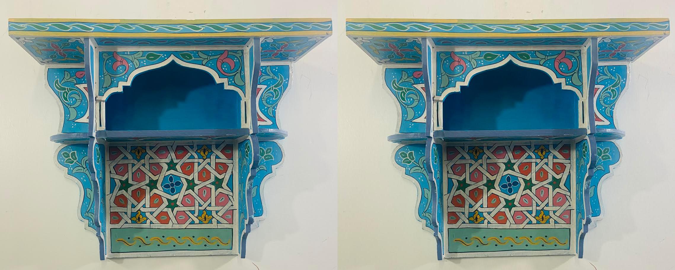 A stunning pair of vintage hand painted Moroccan spice shelves or racks. The shelves are finely hand painted featuring fine moorish and arabesque motifs, painted in light blue and decorated with multicolor designs. Each rack has two shelves , top