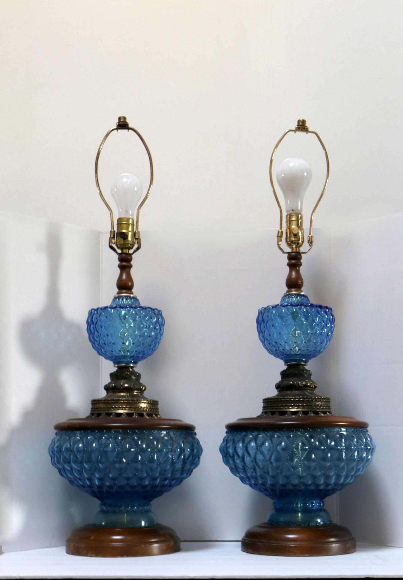 The hobnail blue glass and lustrous patina of the maple wood base and center makes this pair of lamps stand out. The color and texture combination between the wood and the hobnail produces an attractive contrast. They are circa 1960 and have round