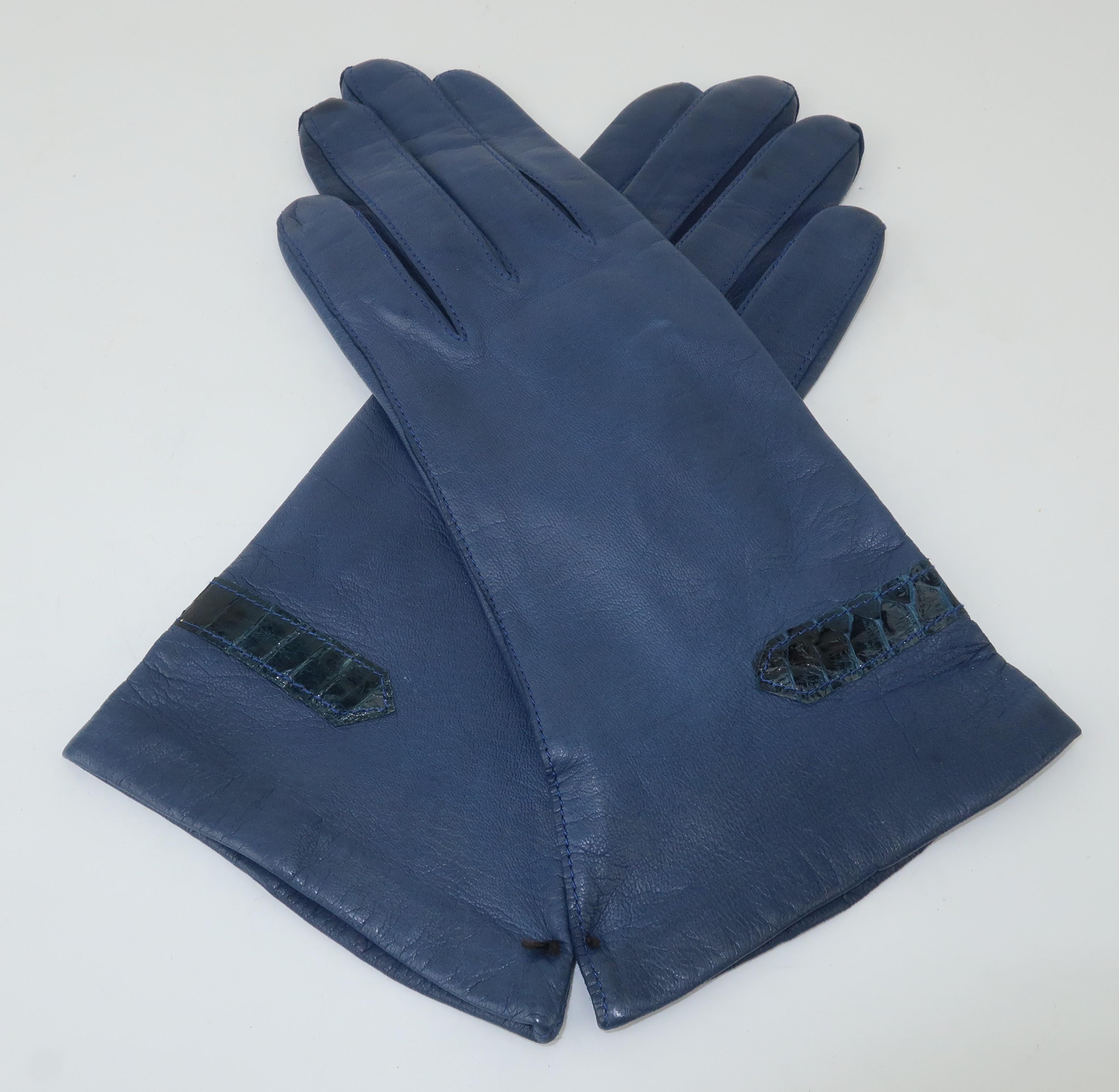 These classy navy blue leather gloves will add a touch of elegance to your winter wardrobe. The gloves feature a coordinating snakeskin detail in an arrow shape at the wrists.  Lined with nylon and appear to be never worn with original blue stitch