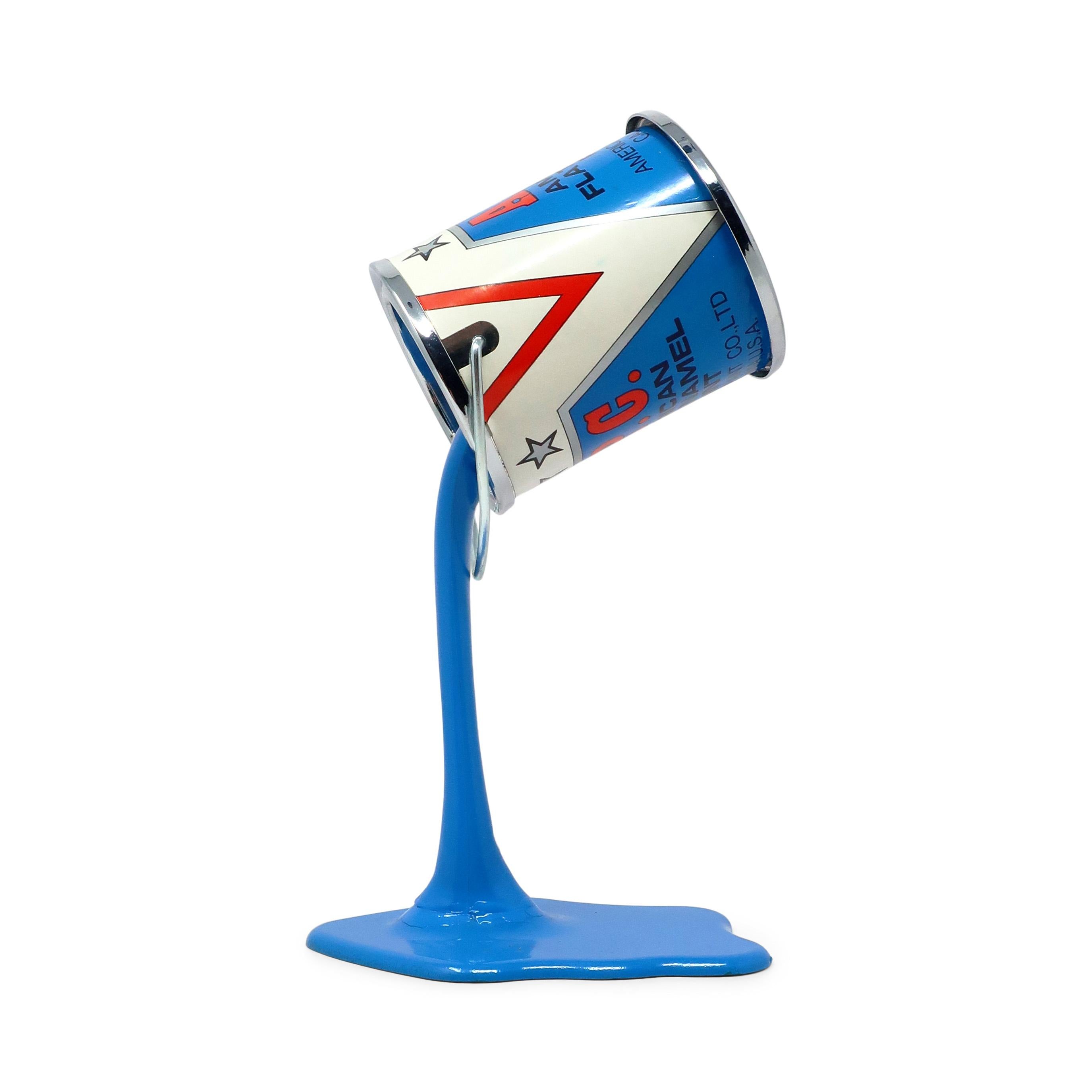 Une tirelire/sculpture en forme de canette de peinture parfaitement Pop Art des années 1980.  Un pot de peinture en métal dont le fond est percé d'une fente pour pièces de 25 cents semble défier la gravité en reposant sur un flot de peinture en