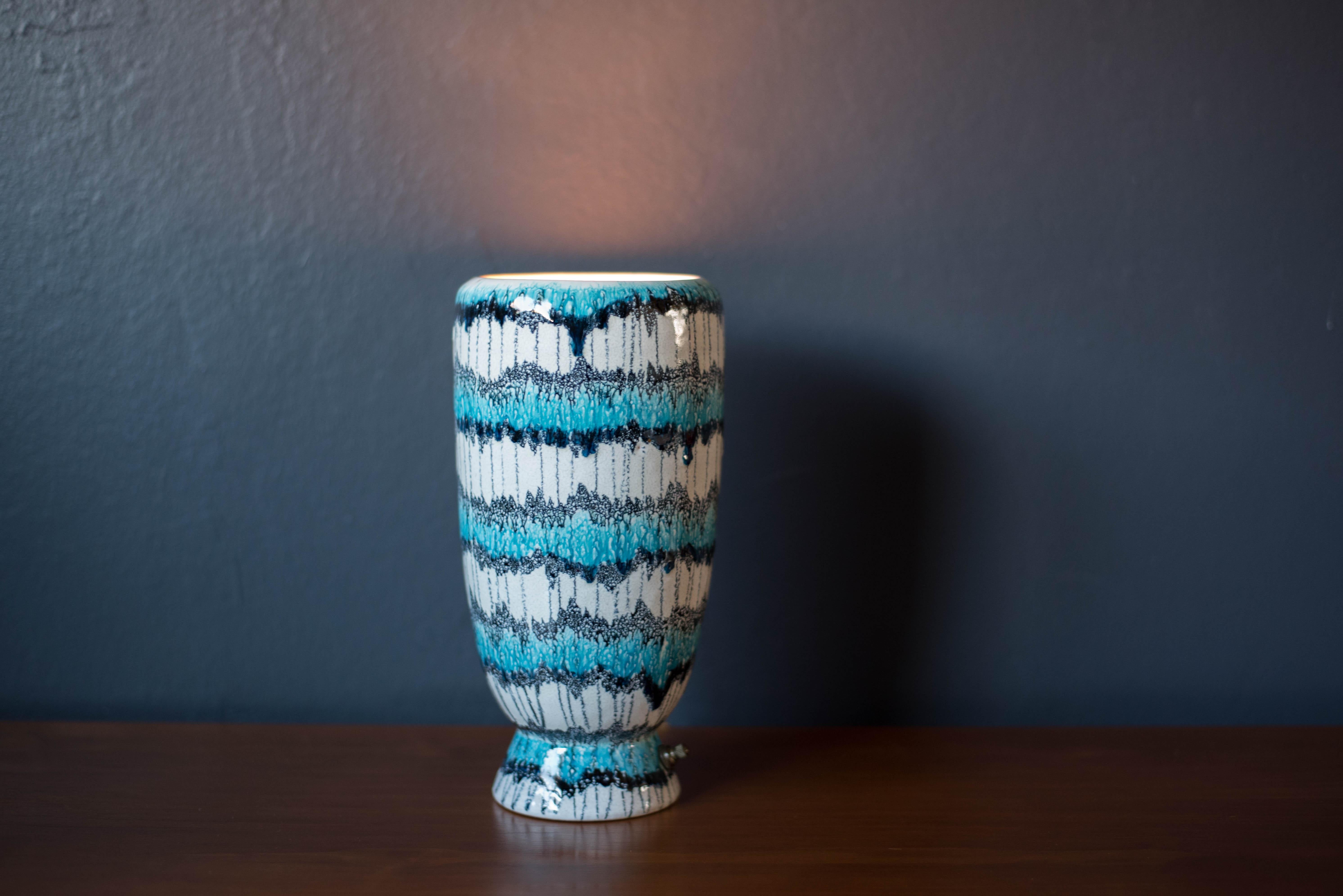 Mid century modern ceramic stoneware pottery table lamp circa 1960's. Features a white ceramic base with a bright color glaze finish in light blue and black. Equipped with a brass switch that emits a soft warm glow. Signed 'Crelsca' on the bottom. 