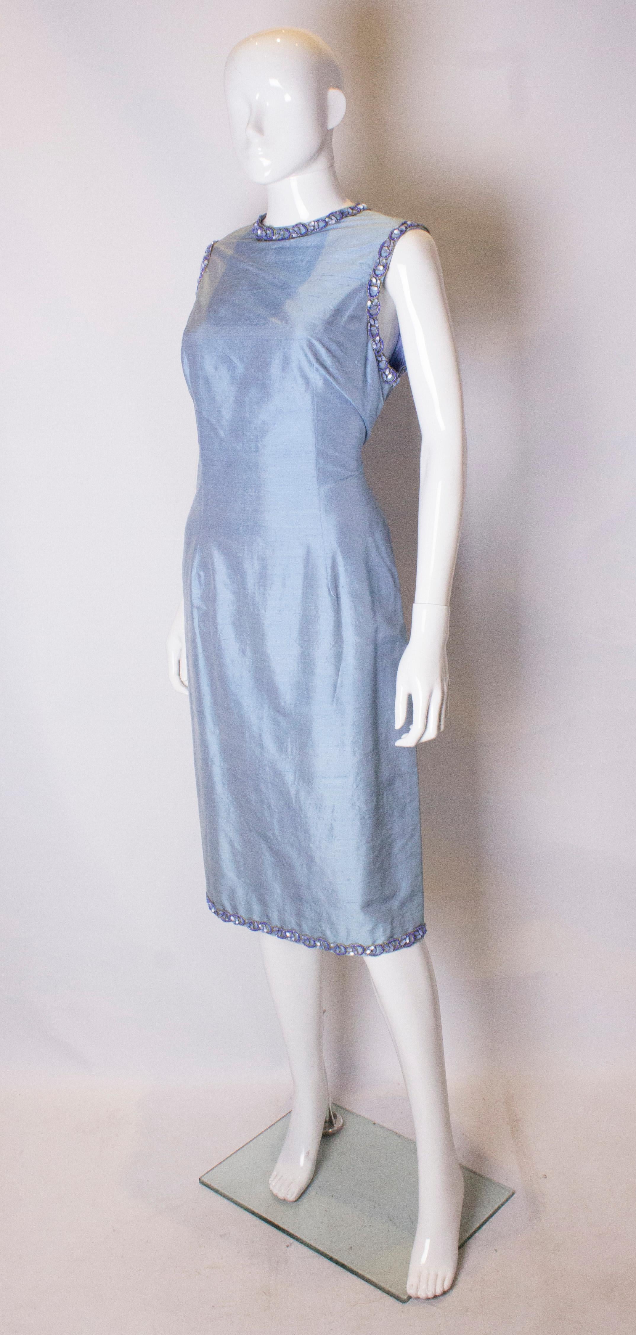Ein schickes himmelblaues Vintage-Cocktailkleid aus Rohseide. Diese Verschiebung Stil Vintage Cocktail-Kleid hat hübsche Perle Detail auf dem Ausschnitt, Arm Löcher und Saum Es ist voll Linie mit einem zentralen Reißverschluss auf der Rückseite, und