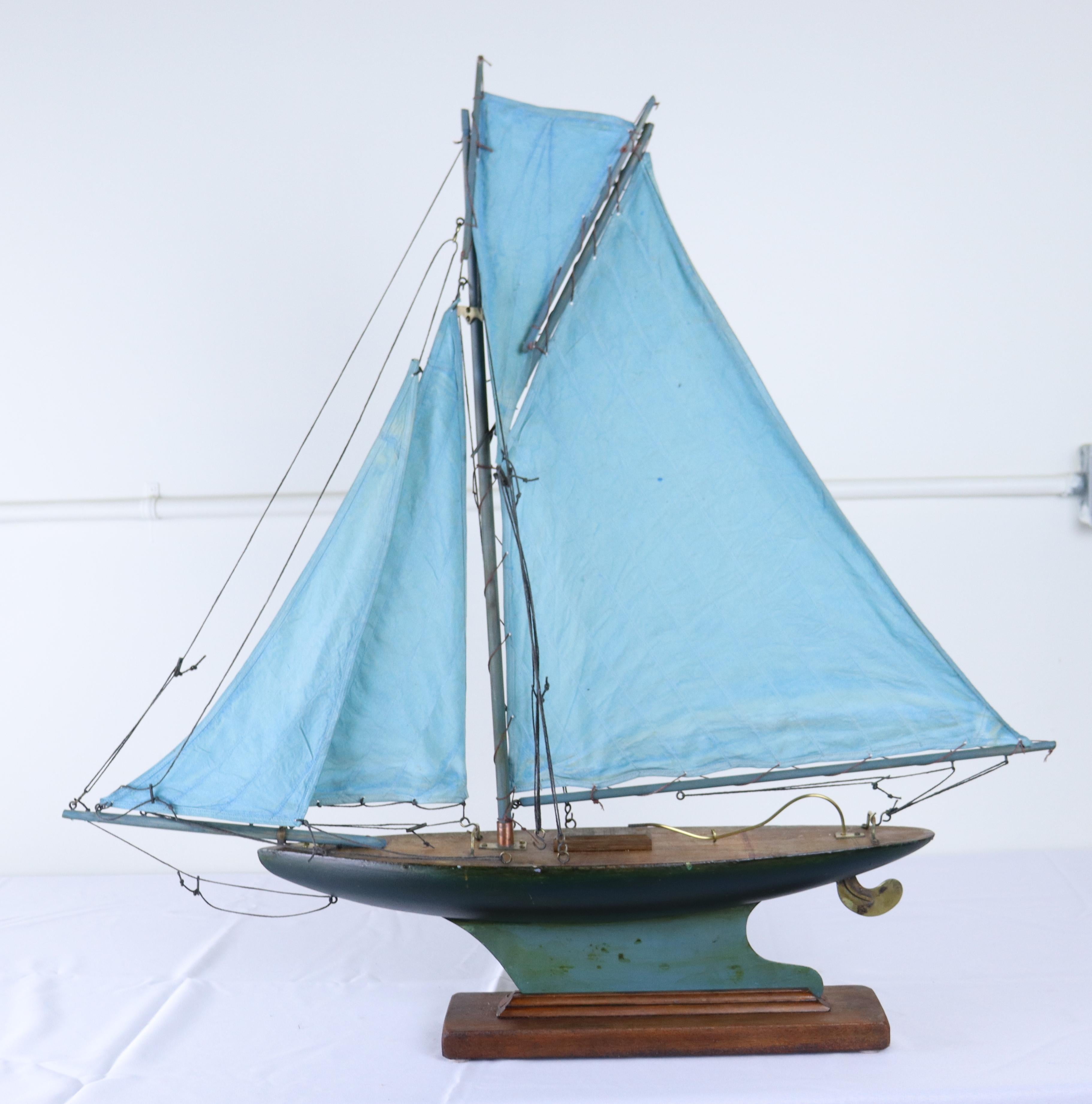 A charming vintage model yacht with sails made from old blue sail cloth and original brass accents.  Stand is recent to hold the ship upright and stabile.  Measurements include the stand.  If you need 2, we have another with blue sails and identical