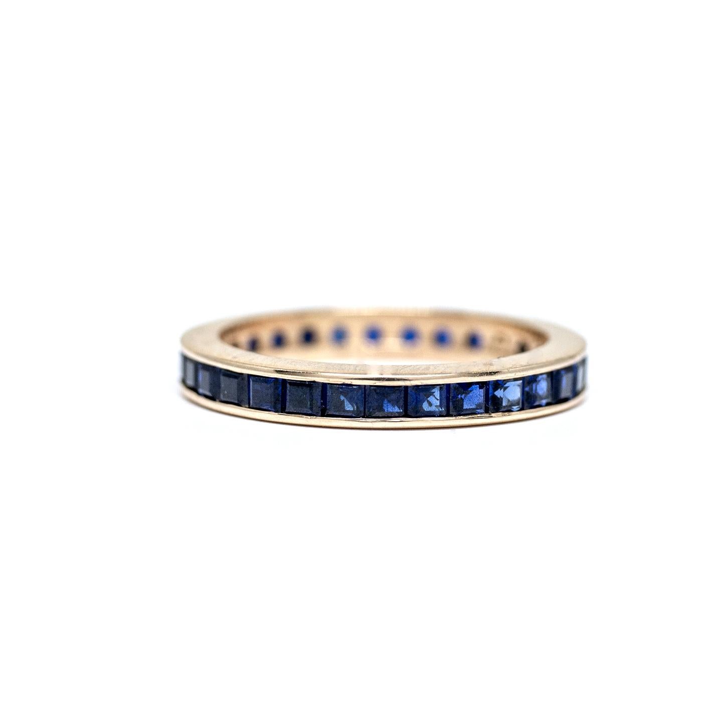 Description: 
This piece is a 1950's eternity band crafted of 14 karat yellow gold holding a carat of high quality synthetic blue sapphires!  A perfect band with a pop of color with beautiful royal blue sapphires that will pair with your engagement