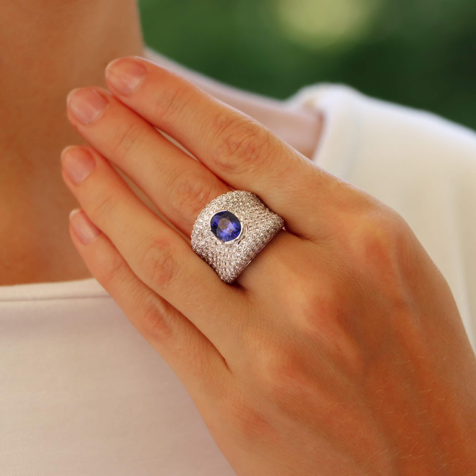  A beautiful vintage blue sapphire and diamond bombe dress ring set in 18k white gold.

This unique piece is composed in a bombe design and is centrally set with a vibrant oval cut blue sapphire stone. The sapphire is bezel set securely amongst a
