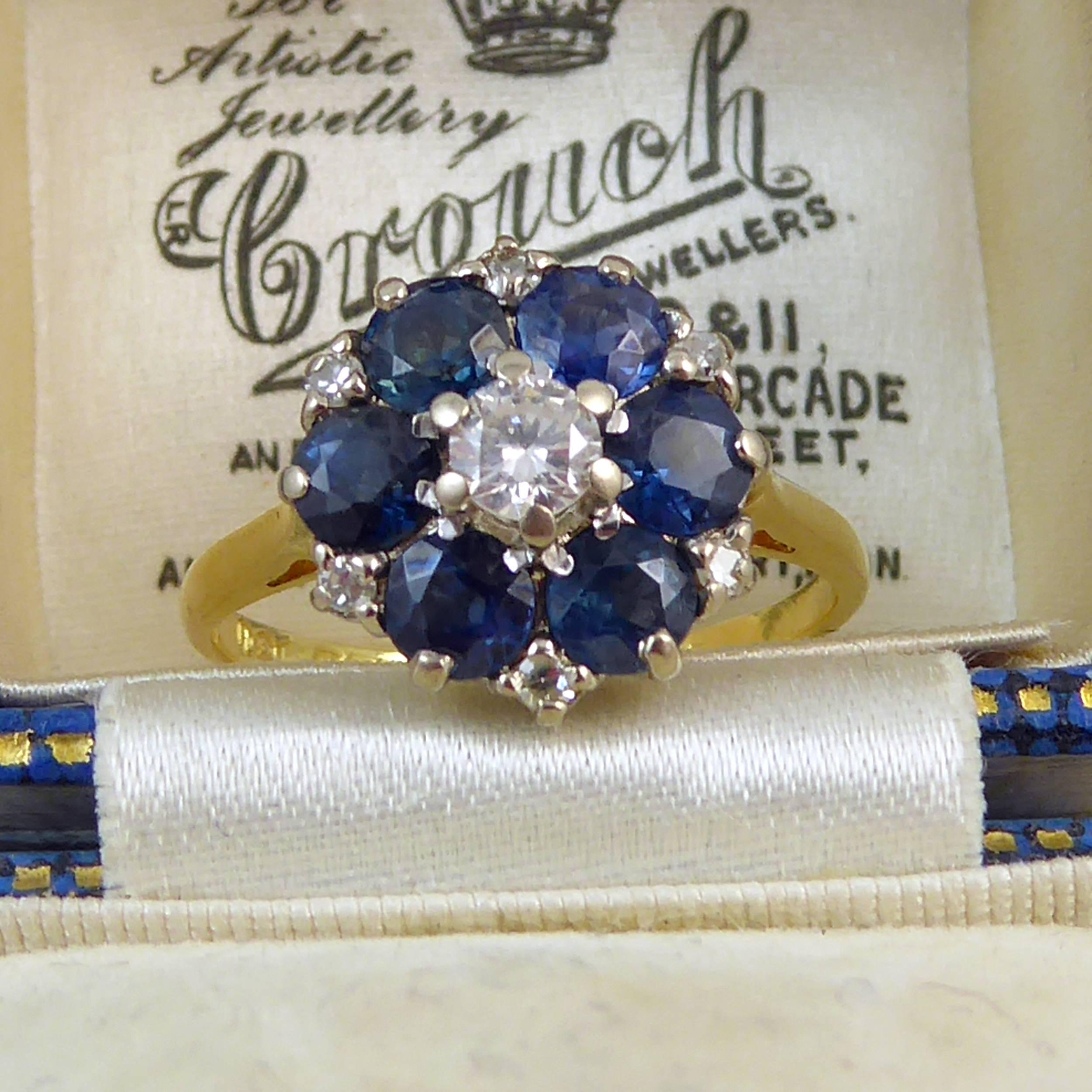 A vintage engagement ring in a classic cluster style and set with a traditional arrangement of blue sapphires with diamond.  Set to the centre with a round brilliant cut diamond measuring 3.6mm diameter x 2.2mm deep, approx. 0.16ct, held in six