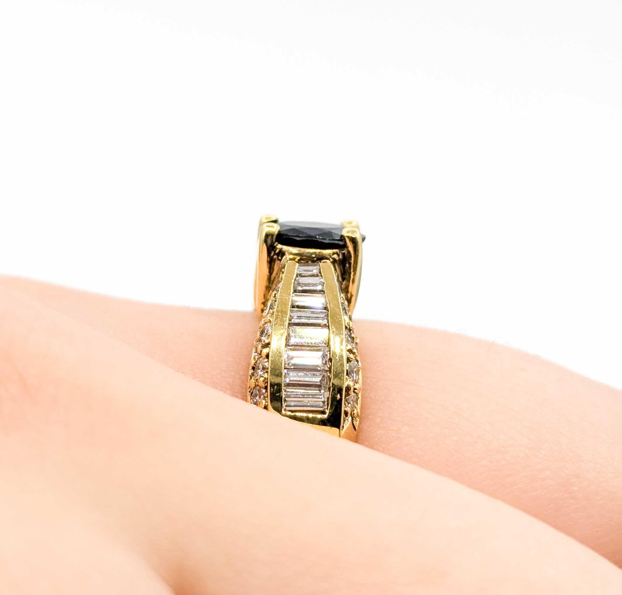 Questo anello è realizzato in oro giallo 18 carati e presenta uno zaffiro blu ovale da 1,10 carati accentuato da 1,50 carati di diamanti rotondi e baguette. Il design a crossover diviso mette in risalto la tonalità profonda dello zaffiro e aggiunge