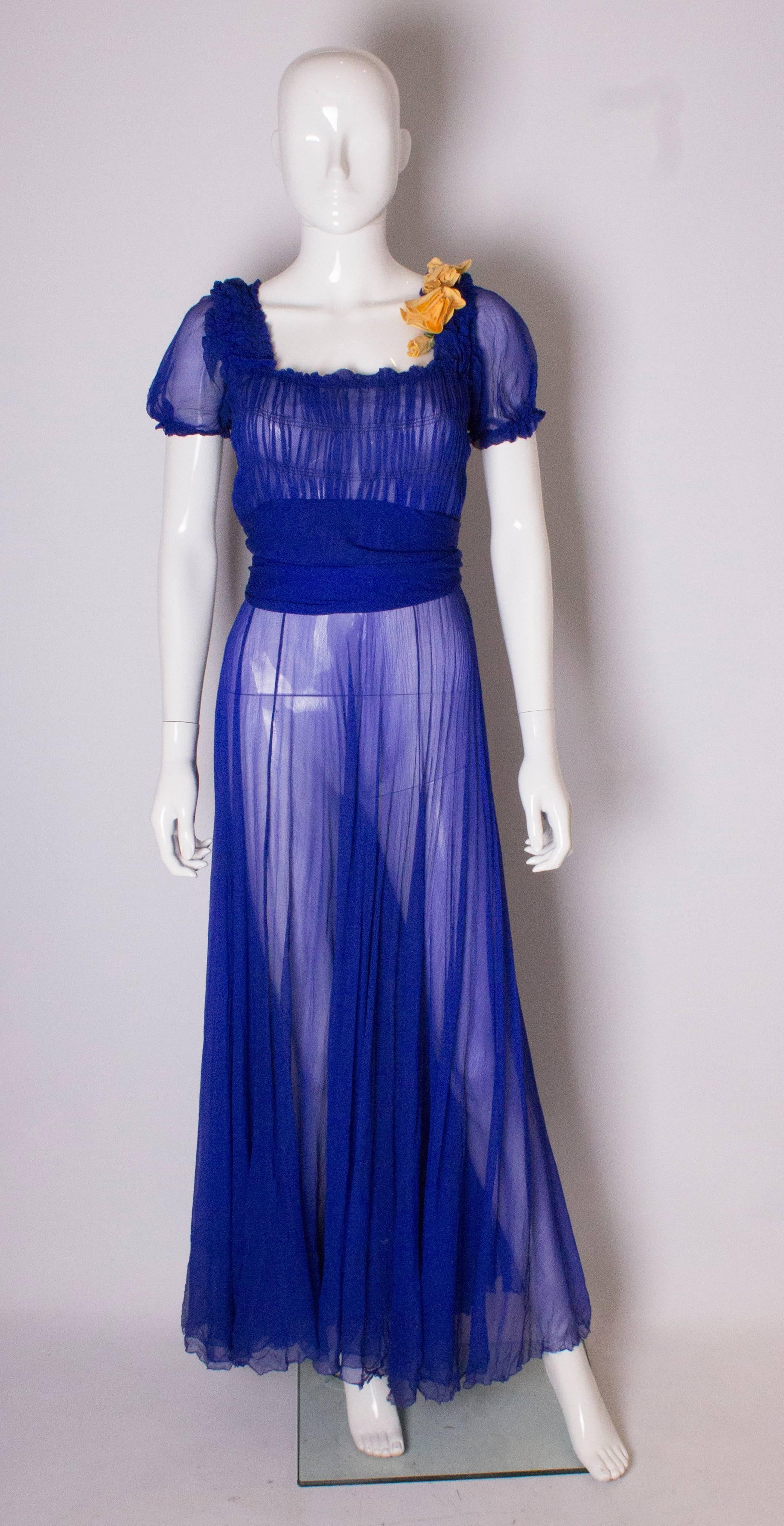 A stunning silk chiffon gown  in a wonderful vibrant blue . The gown has puff sleeves , gathering over the bust and a wide sash waistband. It has a popper opening at the side and a another layer of silk as an underskirt.