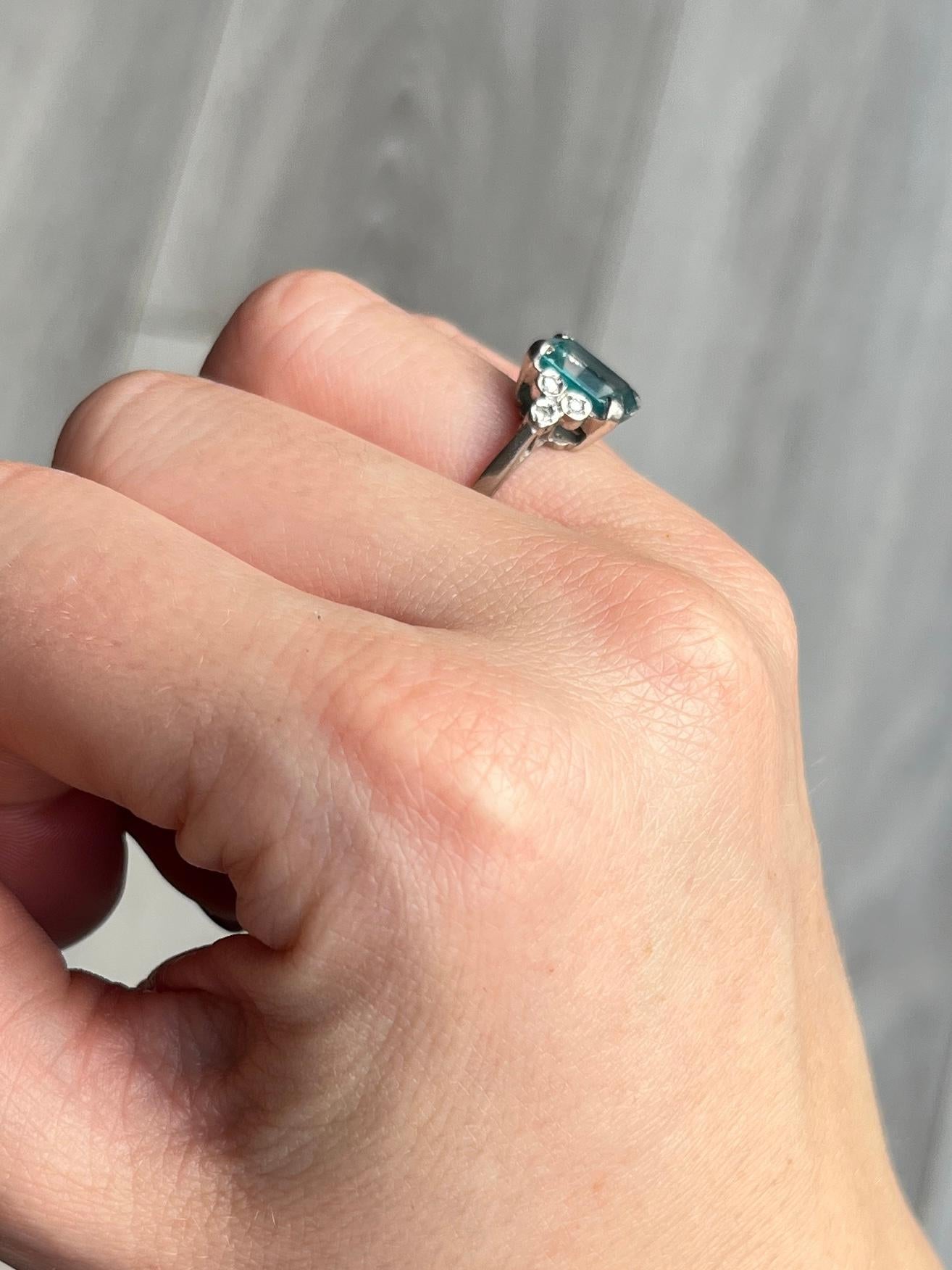 Striking blue topaz set simply in 9 carat white gold and sat either side is a  trio of diamonds. Topaz measures 1.5carat and the diamond total is 12pts. Fully hallmarked London 1975.

Ring Size: J or 4 3/4
Topaz Dimensions: 10x7.5mm
Height Off