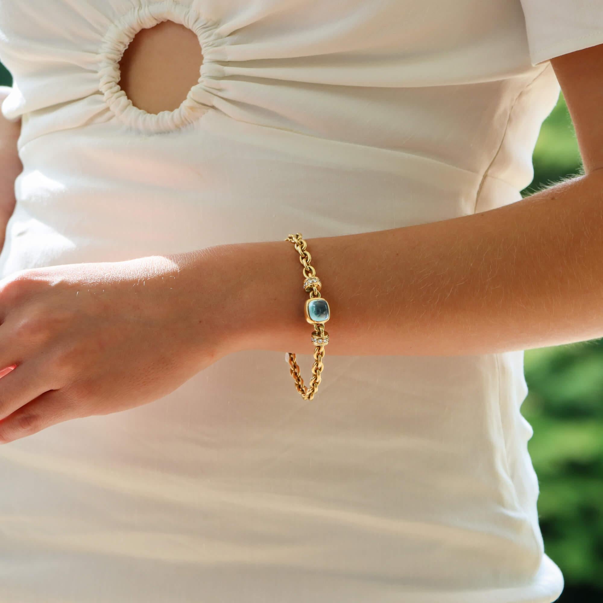  Ein wunderschönes Vintage-Armband aus Blautopas und Diamanten in 18 Karat Gelbgold.

Das Armband ist in der Mitte mit einem blauen Topas besetzt, der als Cabochon geschliffen ist und durch Reiben sicher befestigt wurde. Auf jeder Seite befindet