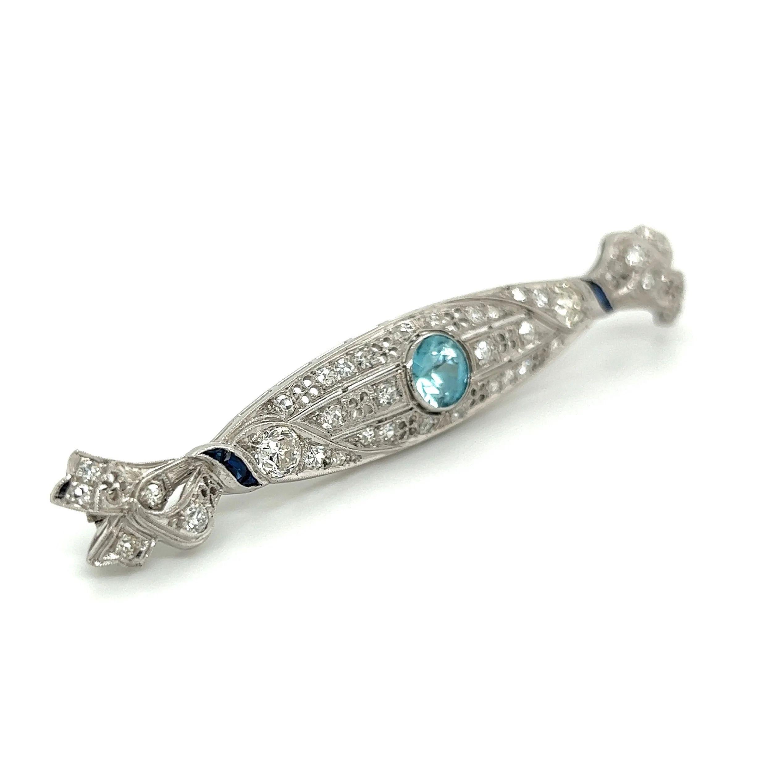 Simply Beautiful! Art Deco Blue Zircon Diamond and Sapphire Platinum Stylized Ribbon Bar Brooch Pin. Centering a 1.47 Carat Round Blue Zircon. Surrounded by Diamonds, approx. 1.28tcw and accented by Sapphires. Measuring approx. 2.75