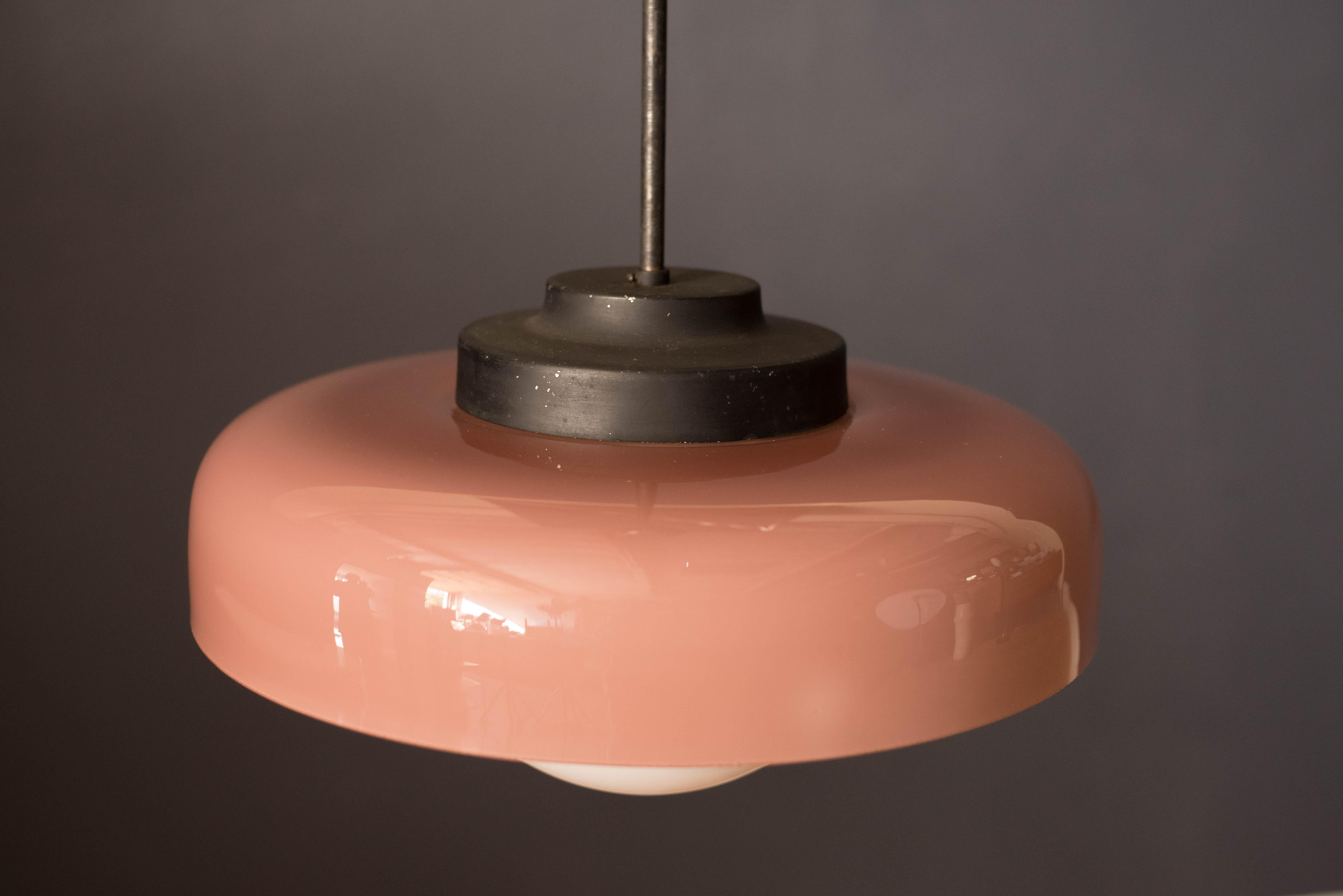 Mid-Century Modern hanging glass pendant, circa 1960s. This Classic light fixture gives a soft glow with an architectural element. Includes a two-toned blush pink shade with white interior, round glass globe, plus hanging metal rod and ceiling plate