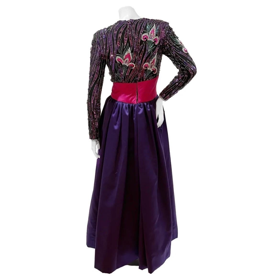 Vintage Purple Sequin Mardi Gras Gown by Bob Mackie Boutique
Circa 1980s
Purple/pink
Long sleeve
Purple and pink floral beaded and sequin embellishment
Front pink bow and waist detail
High neckline 
Zip cuff closure
Back zip closure
Skirt lining