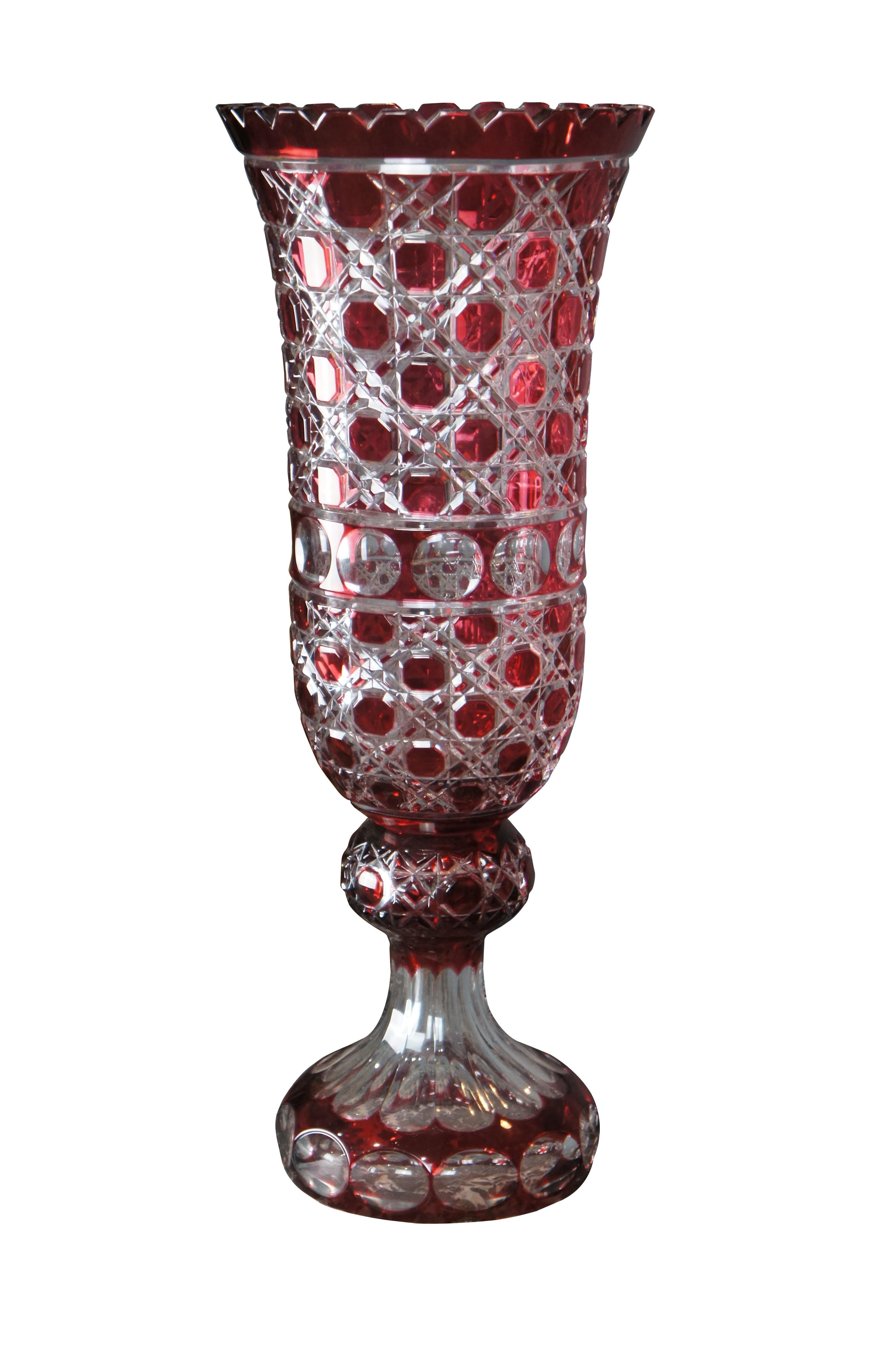 An impressive vintage Bohemian ruby cut to clear crystal vase. Features a coin dot and lattice pattern with sawtooth flared mouth. The vases is poised on a footed base.

Dimensions:
21