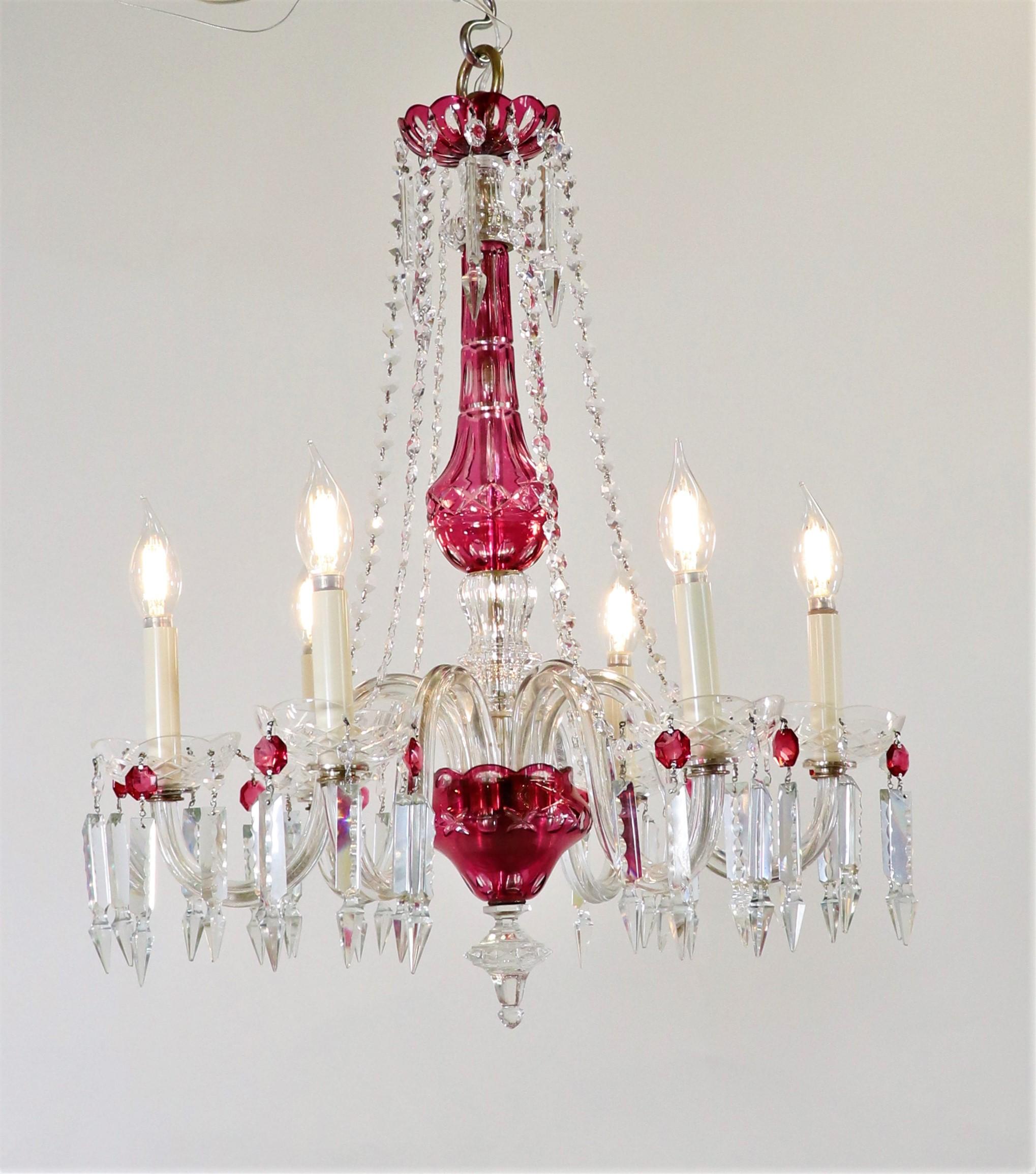 This vintage Bohemian etched crystal chandelier has undulating arms holding scalloped bobeches surrounding a bulbous center column. Crafted with clear and cranberry crystal, this six-light chandelier will bring a luxurious ambiance to any room. The