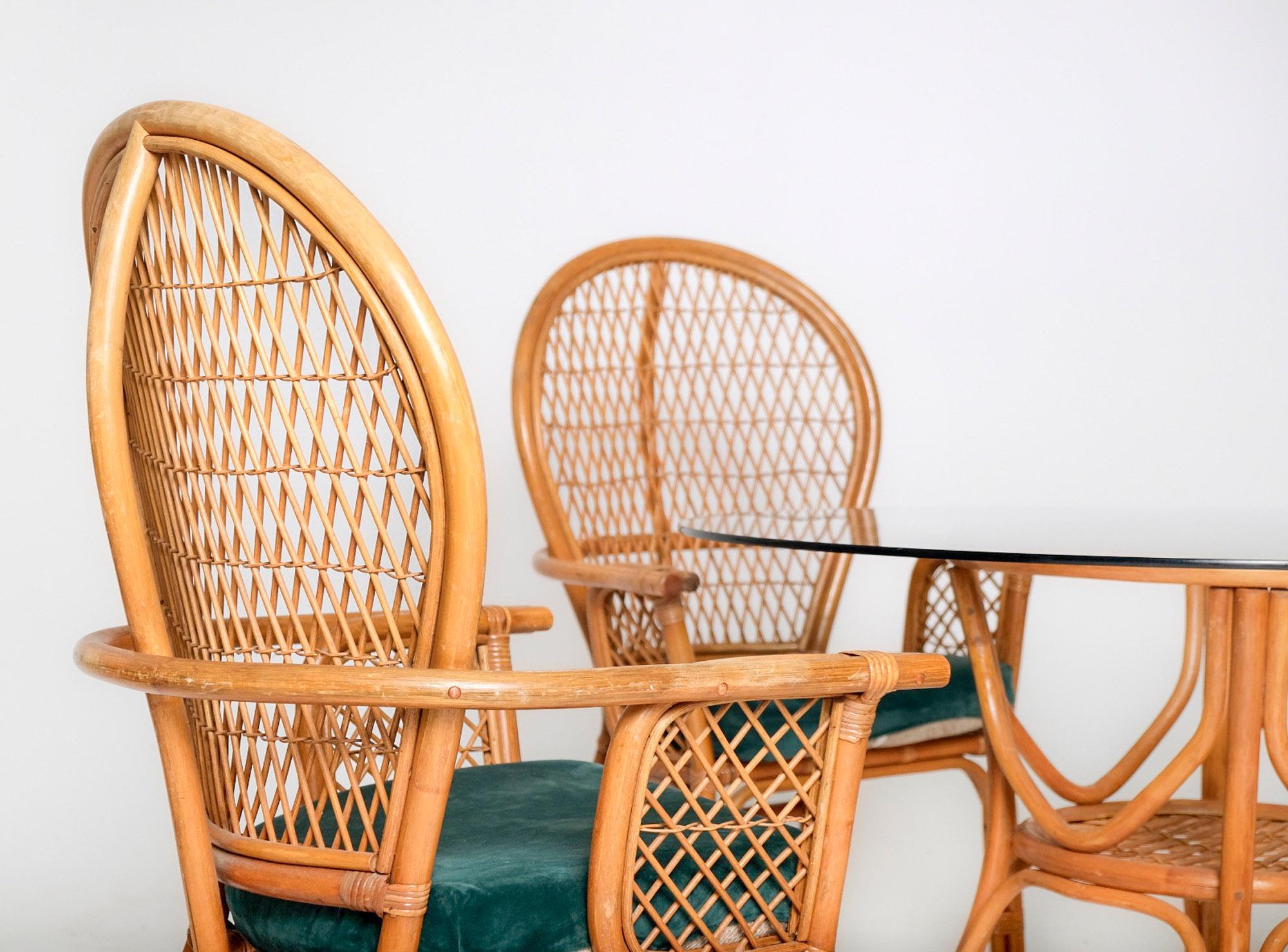 A beautifully preserved 1970s rattan dining set that embodies the relaxed elegance of California coastal and tropical modern design. This five-piece set includes a sculptural round rattan table base with an inset glass top and four high-back
