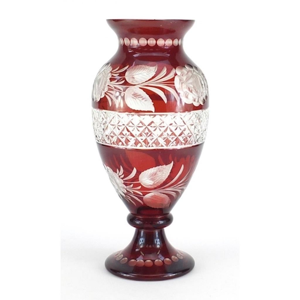 Bohemian ruby glass vase is an original decorative object realized in the mid-20th century by Czech manufacture. 

This artwork is decorated with cut-glass roses and a central band of criss-cross patterning. 

This beautiful and very precious