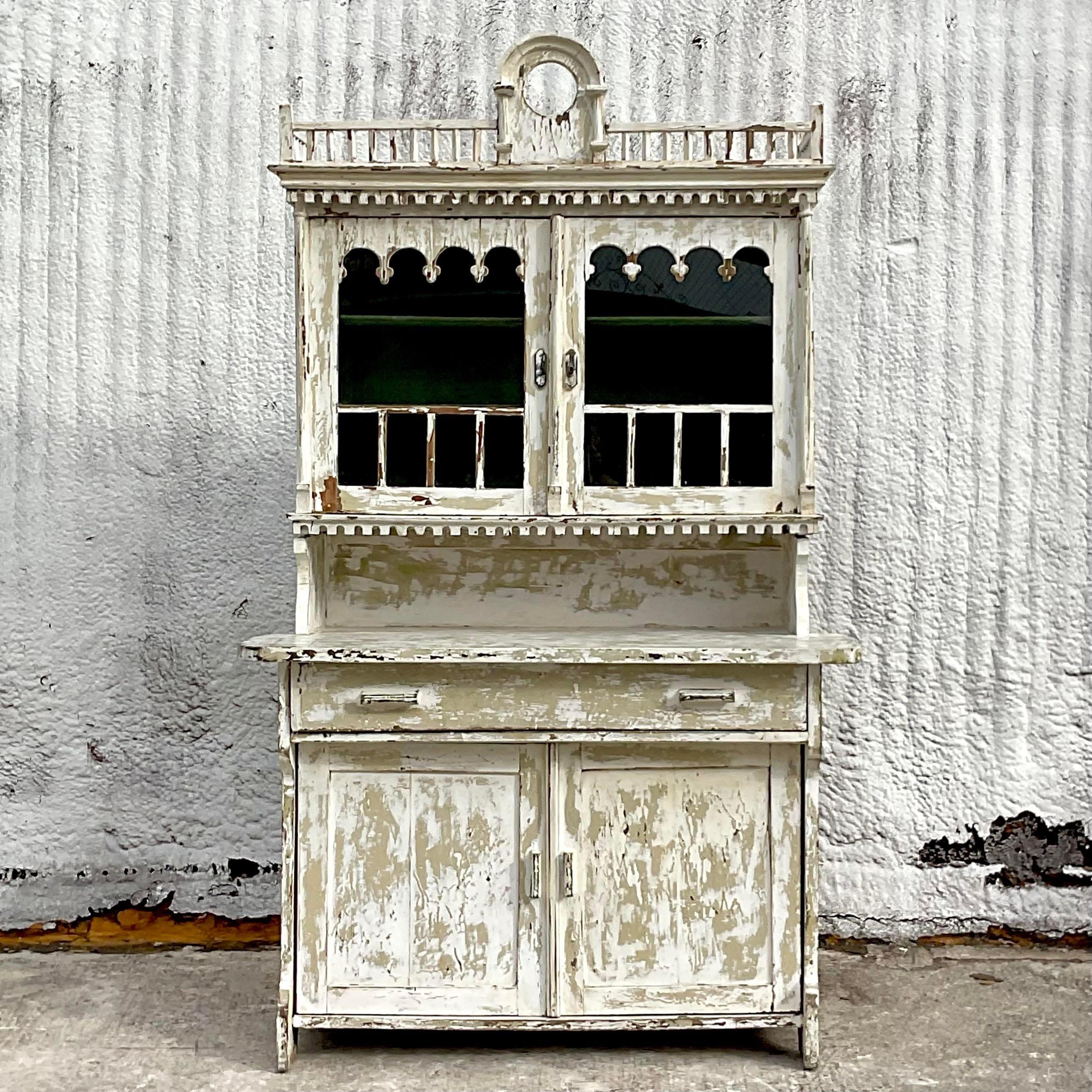 An incredible vintage Boho 19th Century China cabinet. Striking hand chamfered pine with original Oyster white chippy paint. A beautiful all over patina from time. Beautiful film Millwork detail. Acquired from a Palm Beach estate.
