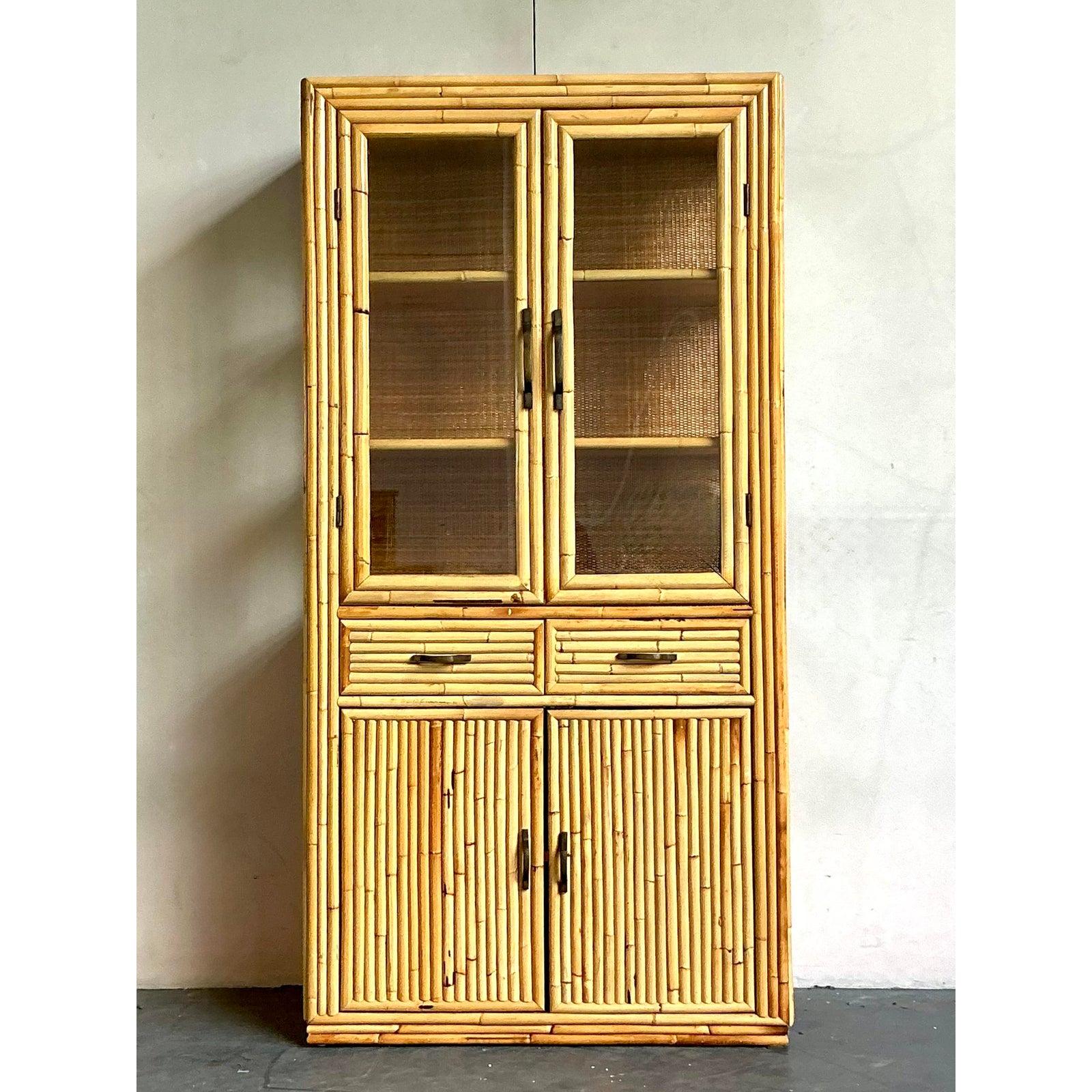 Entdecken Sie die faszinierende Anziehungskraft dieser fünfreihigen Bambusvitrine im Boho-Stil, die mühelos natürlichen Charme mit praktischer Eleganz verbindet. Dieser Schrank ist aus mehreren Strängen von reichhaltigem, honigfarbenem Bambus