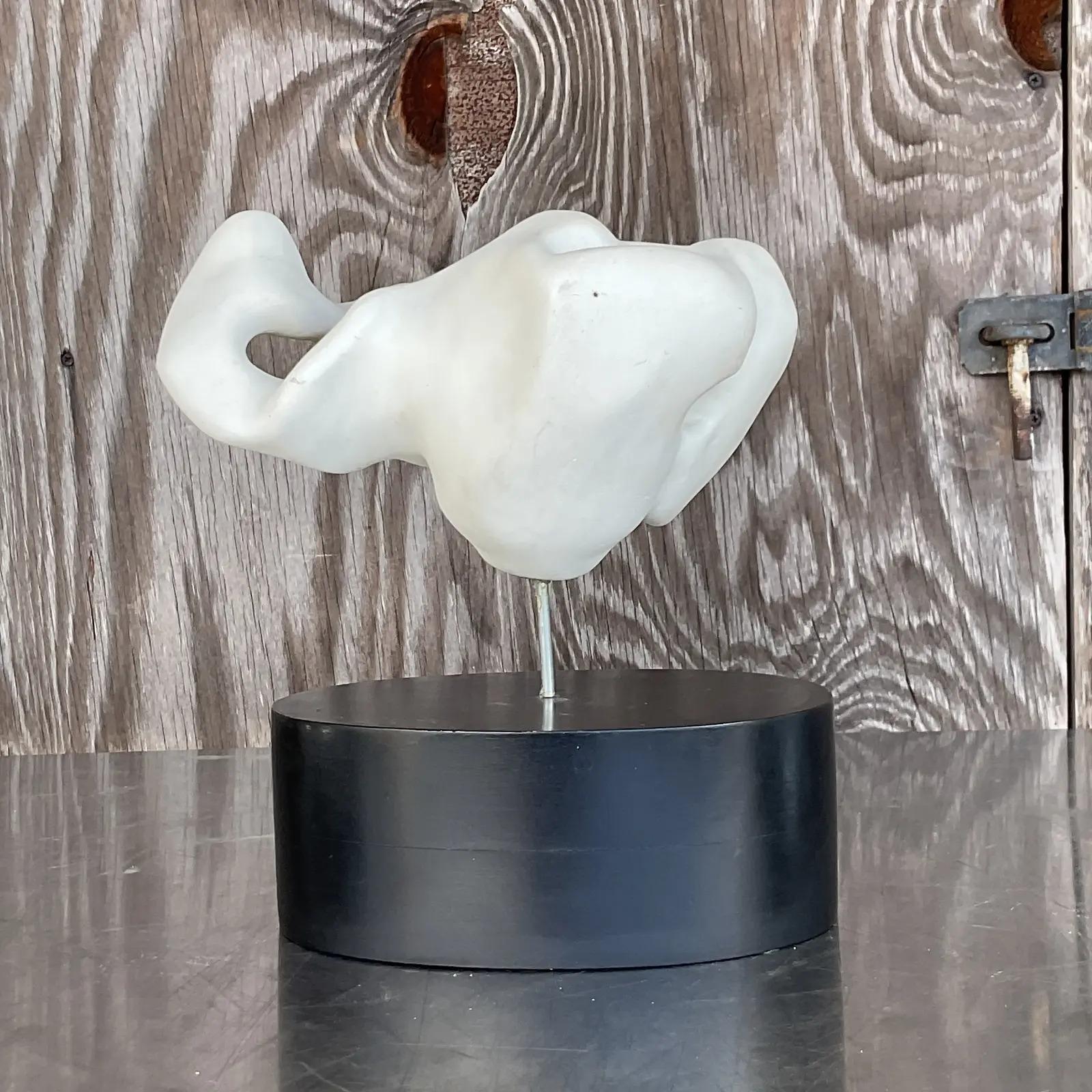 A fantastic vintage abstract sculpture. A plaster composition of a biomorphic shape in bright white. Stands on a black plinth and initialed by the artist. Acquired from a Palm Beach estate.