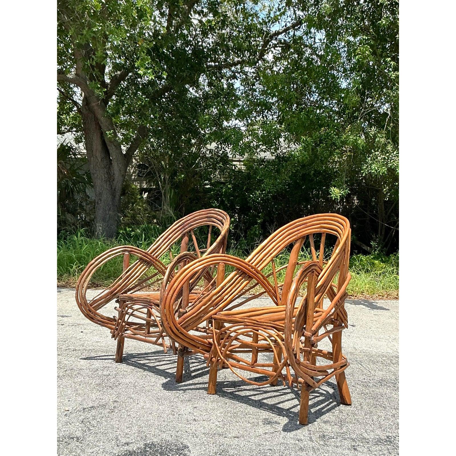 Make a stunning statement with this exceptional pair of vintage Adirondack twig lounge chairs. Masterfully handcrafted from steam-bent rattan, their sculptural silhouette is defined by dramatic, looping arms that create an open, airy, and artistic