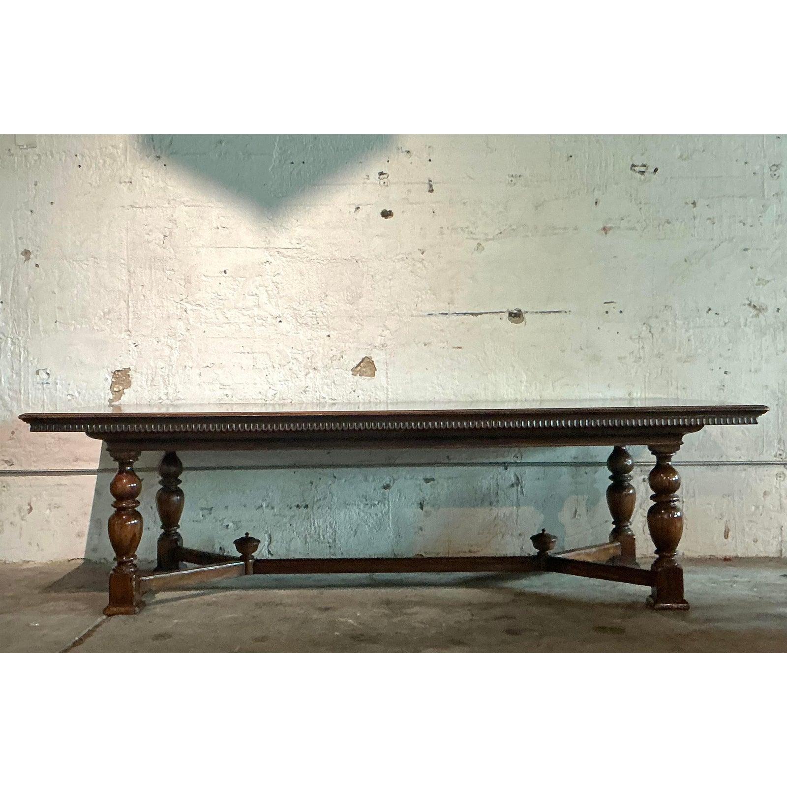 A truly monumental statement of Old World elegance, this exquisite dining table by Alphonse Marina is a masterpiece of rustic craftsmanship. Expertly constructed from solid, dark-stained wood, the table's design is defined by its powerfully turned