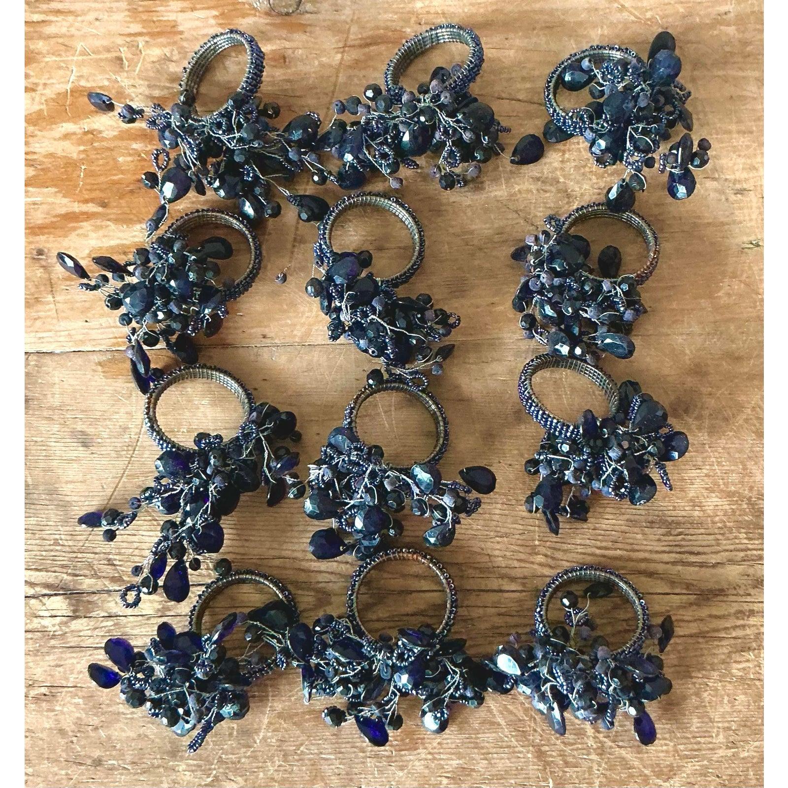 Dieses schillernde Set aus zwölf Serviettenringen mit Vintage-Perlen verleiht Ihren Mahlzeiten stimmungsvolle Eleganz und einen Hauch von Glitzer. Jeder Ring besteht aus einer üppigen, organischen Ansammlung von facettierten Perlen in tiefen