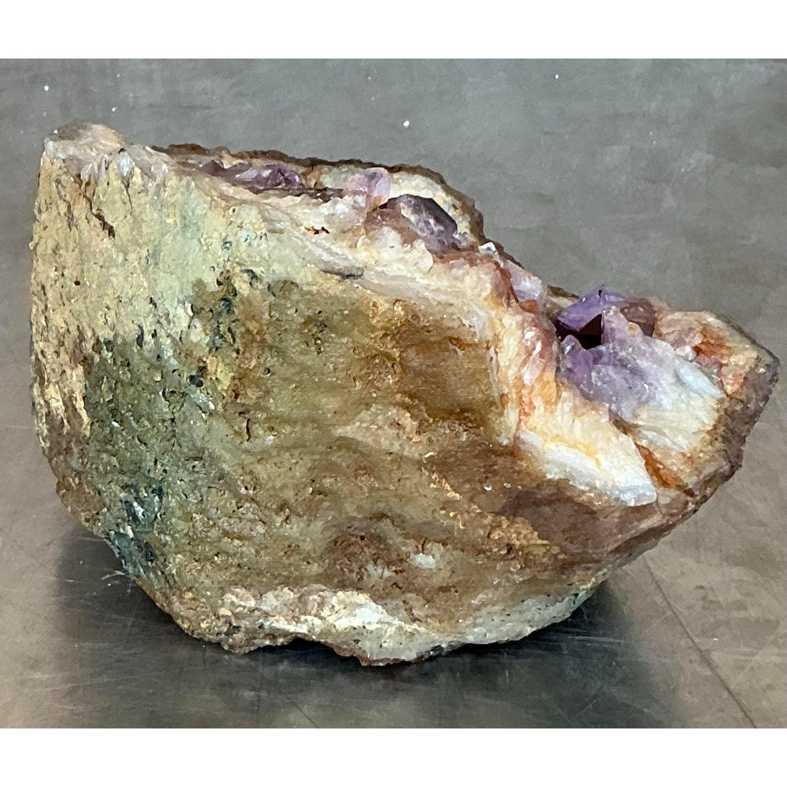 Invita la bellezza grezza della terra nella tua casa con questo splendido geode di ametista vintage, un pezzo perfetto per incarnare un'estetica naturale Vintage Boho. Questo affascinante esemplare di cristallo rivela una cavità abbagliante piena di