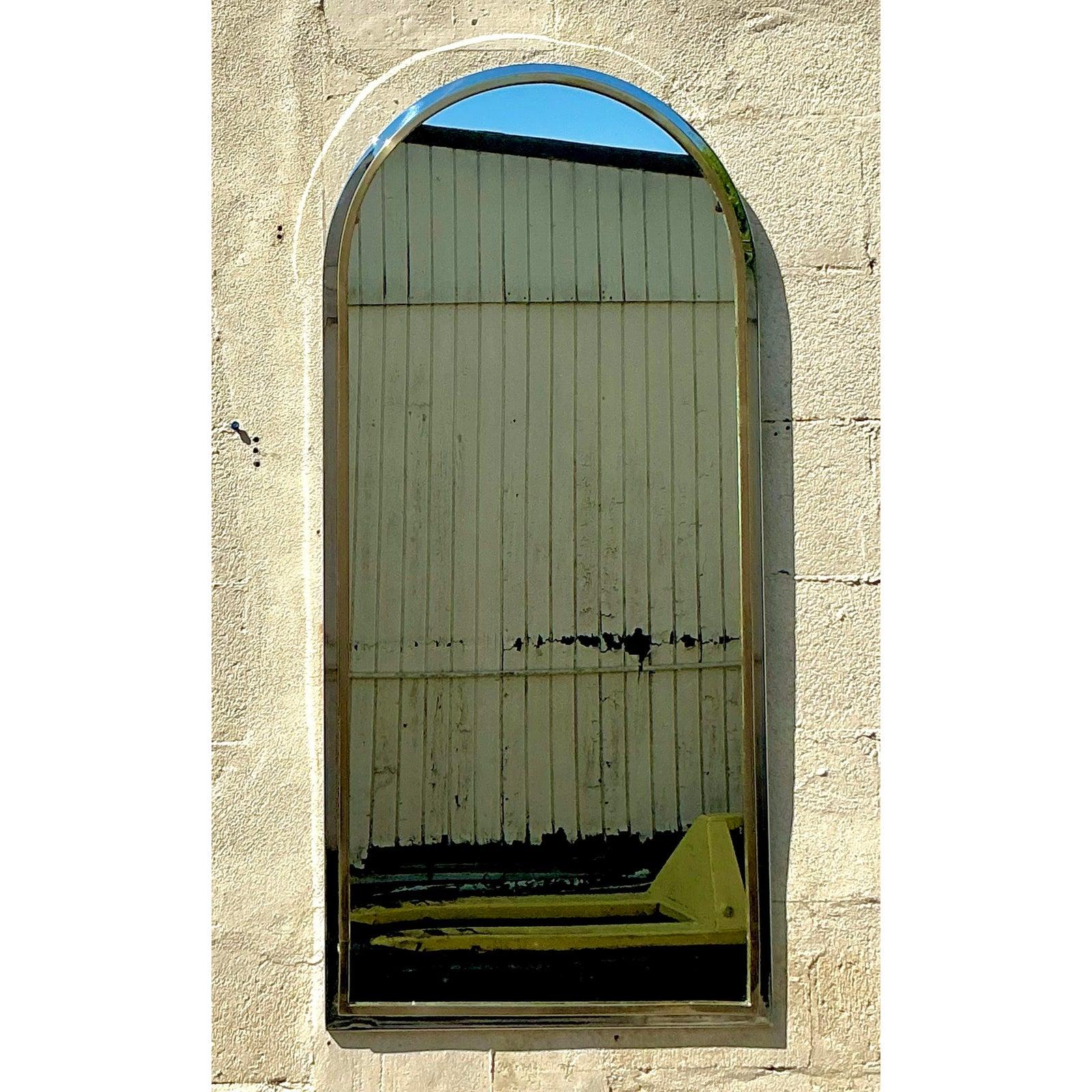Questo splendido specchio ad arco vintage incarna una sofisticata miscela di eleganza boho e raffinatezza moderna. Caratterizzato da una silhouette graziosamente curva, il pezzo è incorniciato da una lucente cromatura con sottili accenti di ottone,