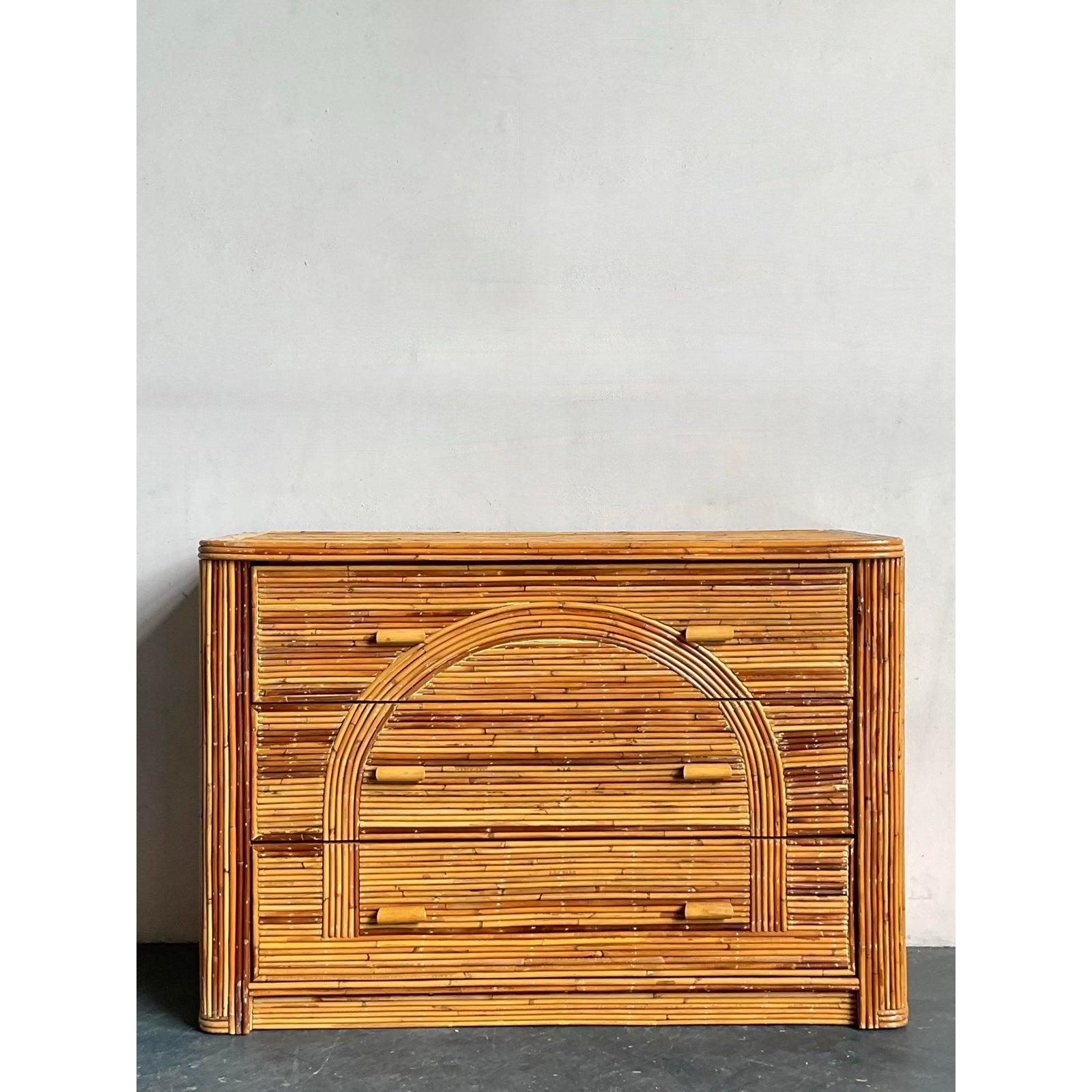 Ti presentiamo un'affascinante cassettiera vintage, un superbo esempio di design Boho Chic con un caratteristico tocco architettonico. Questo pezzo è meticolosamente realizzato in rattan di canna da zucchero, disposto in modo da creare texture