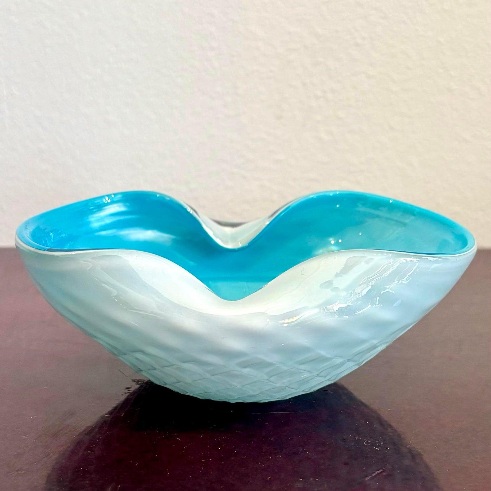 Ce bol en verre d'art soufflé à la main est une étude ludique des contrastes et des flux. Avec son extérieur blanc glacé et son intérieur aqua vif, cette pièce évoque la sérénité côtière, comme la mousse de mer embrassant un lagon turquoise. Le bord