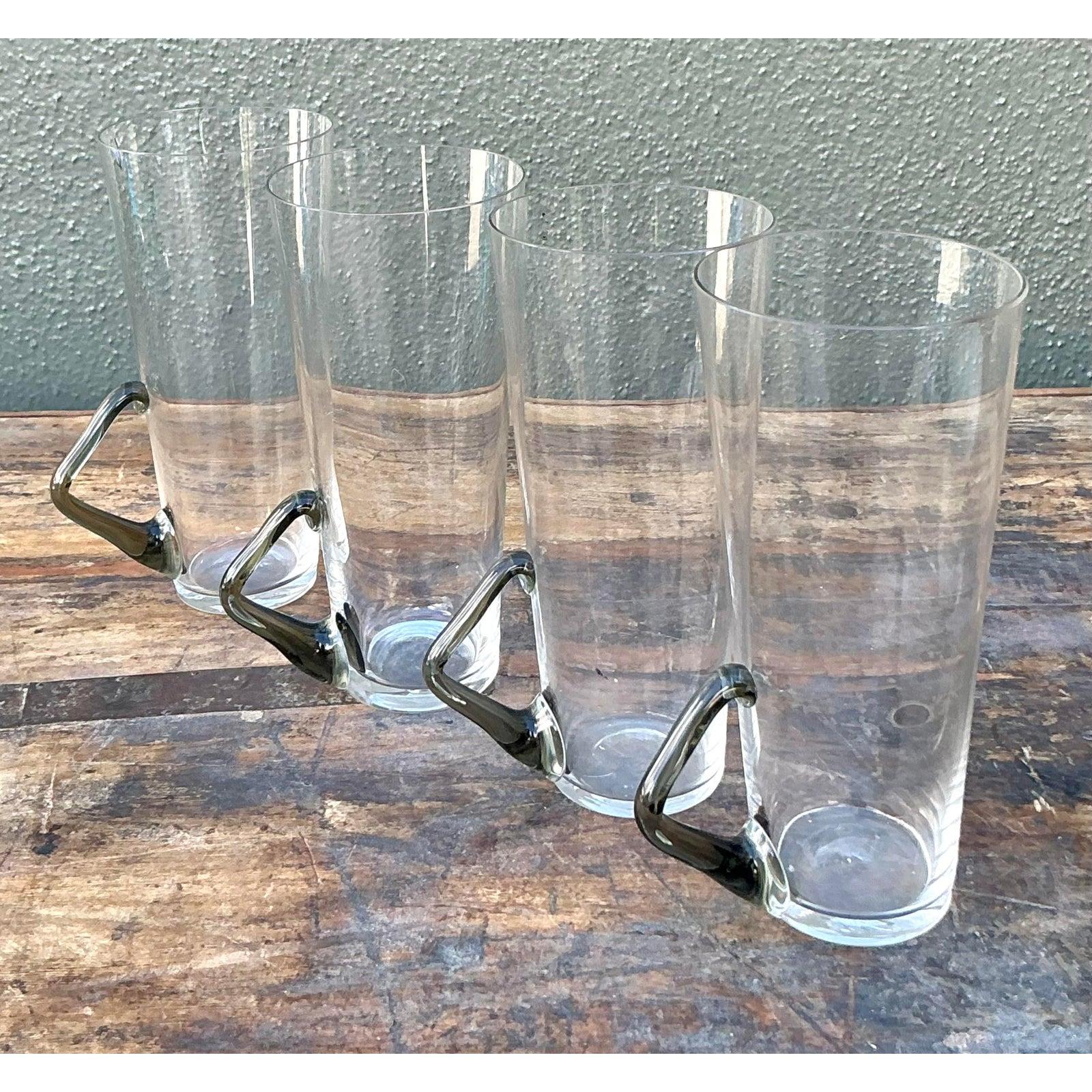 Peppen Sie Ihr Getränkeservice mit diesem raffinierten Set aus vier Highball-Bechern aus Vintage-Glas auf. Jedes Glas verkörpert die postmoderne Ästhetik der 1980er Jahre und hat eine hohe, konisch zulaufende Silhouette, die aus klarem Kristall