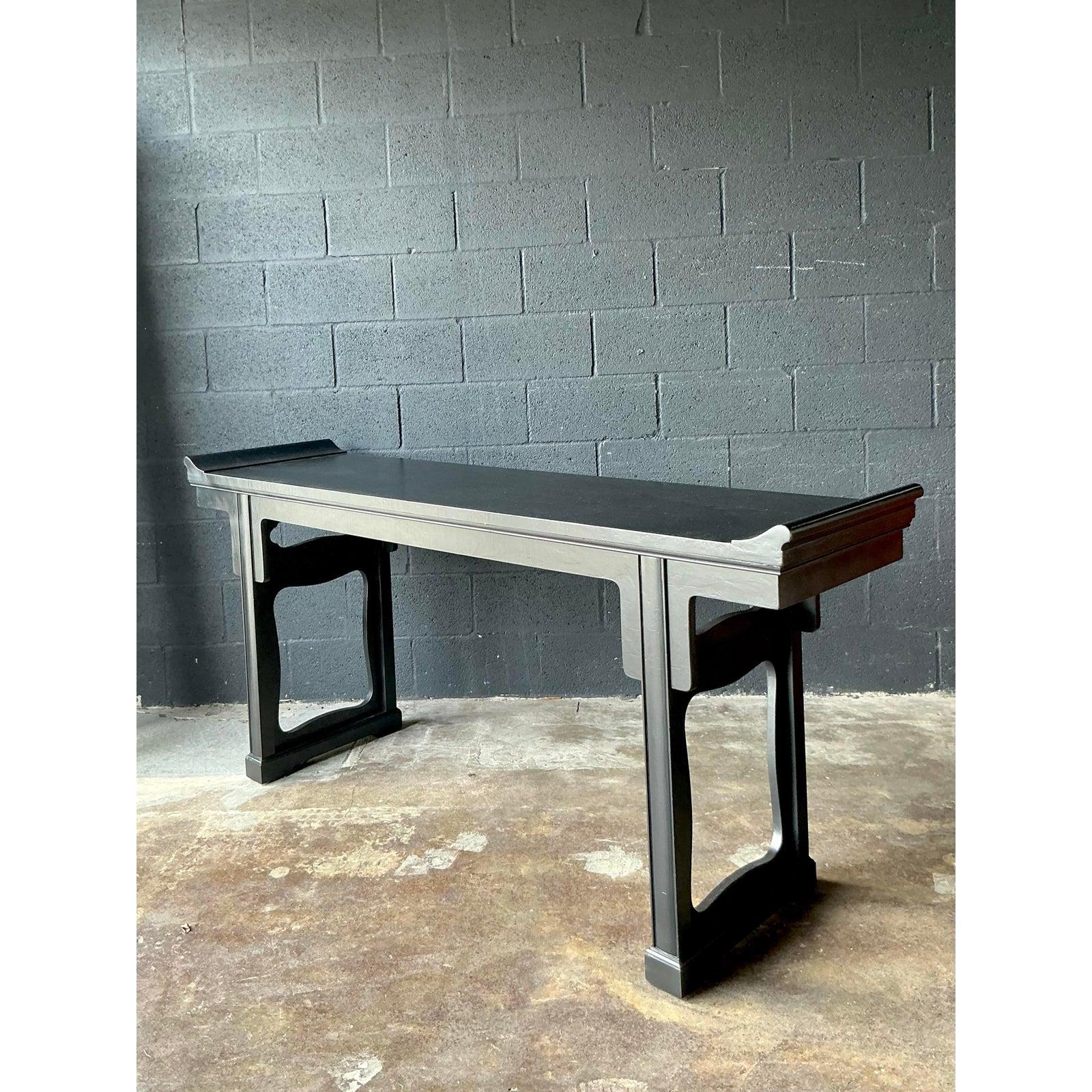 An impressive console table by the esteemed Baker Furniture company, this piece exemplifies a sophisticated fusion of traditional Asian Altar table design and sleek Hollywood Regency modernism. Crafted from solid wood and finished in a striking