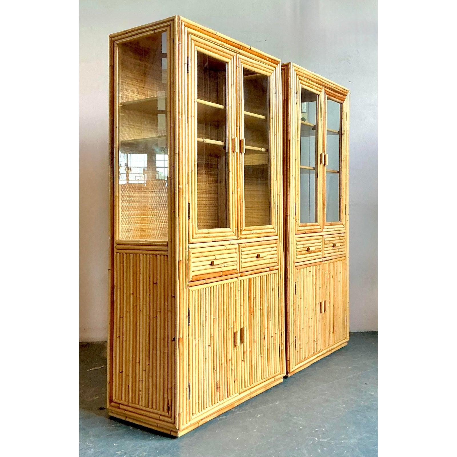 Presenting an exceptional pair of vintage Boho bamboo and rattan display cabinets, embodying a relaxed elegance with a touch of exotic charm. These meticulously crafted cabinets feature a natural bamboo frame, intricately detailed with woven rattan