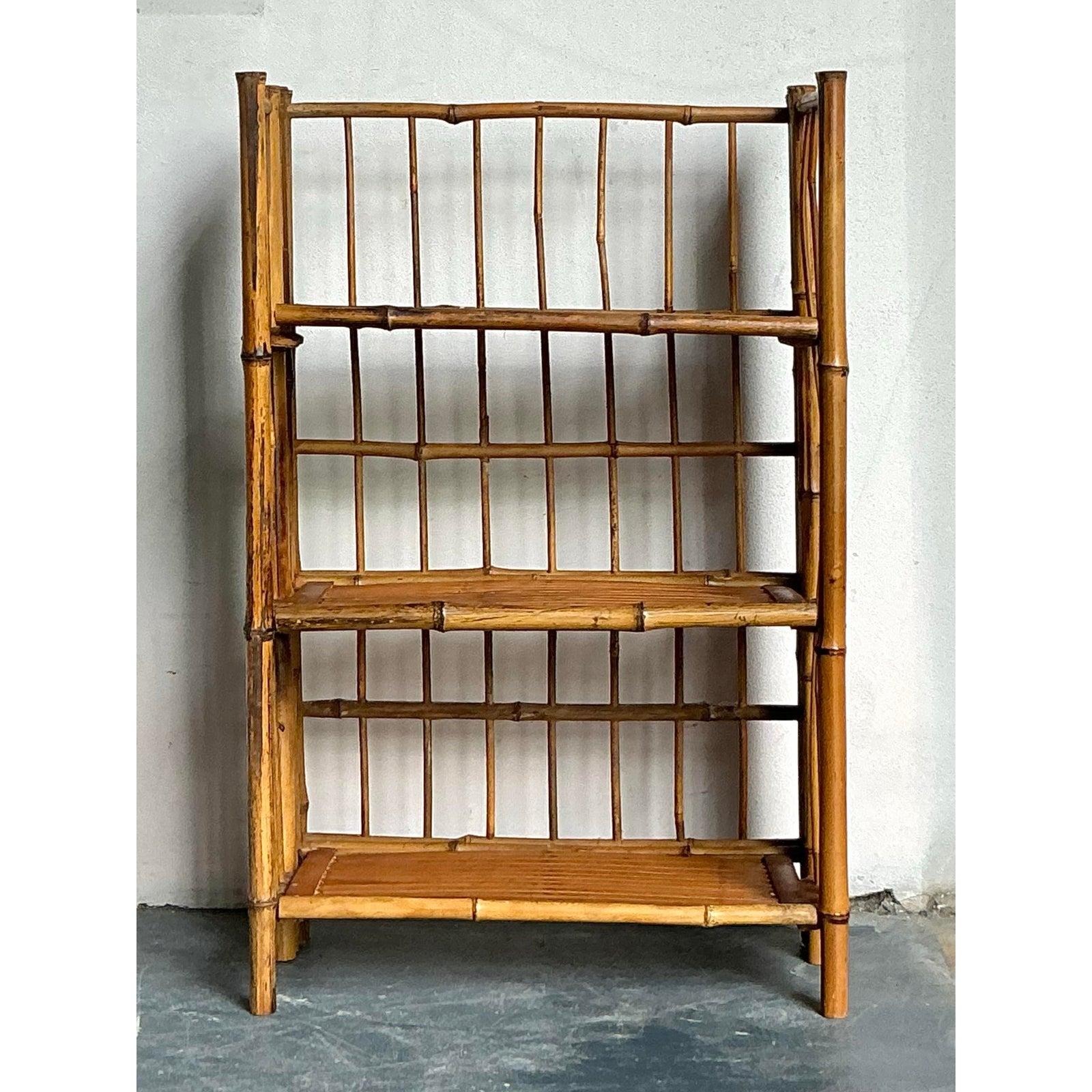 This charming vintage etagere is a quintessential example of tropical and Boho Chic design, crafted entirely from natural bamboo and rattan. Its construction highlights the organic beauty and variability of the materials, featuring thick bamboo