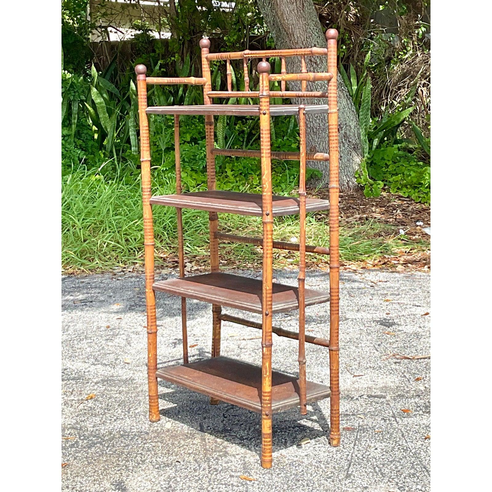 Infuse your space with worldly charm and organic texture with this delightful vintage bamboo etagere. Expertly crafted with a classic faux bamboo frame, this shelving unit features elegant turnings, delicate finials, and a lovely spindled gallery