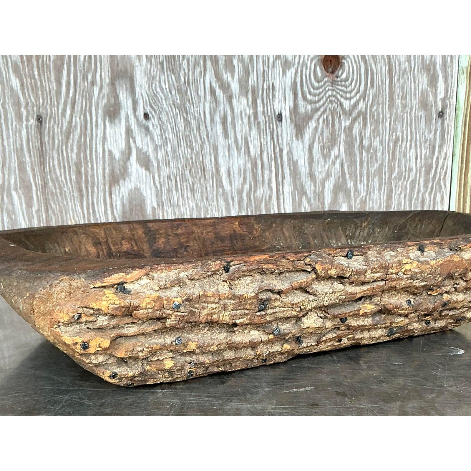 Embrace the raw beauty of nature with this stunning vintage dough bowl, distinguished by its authentic bark-covered exterior. A true embodiment of boho and rustic charm, this substantial wooden bowl showcases a hand-hewn quality, with the natural