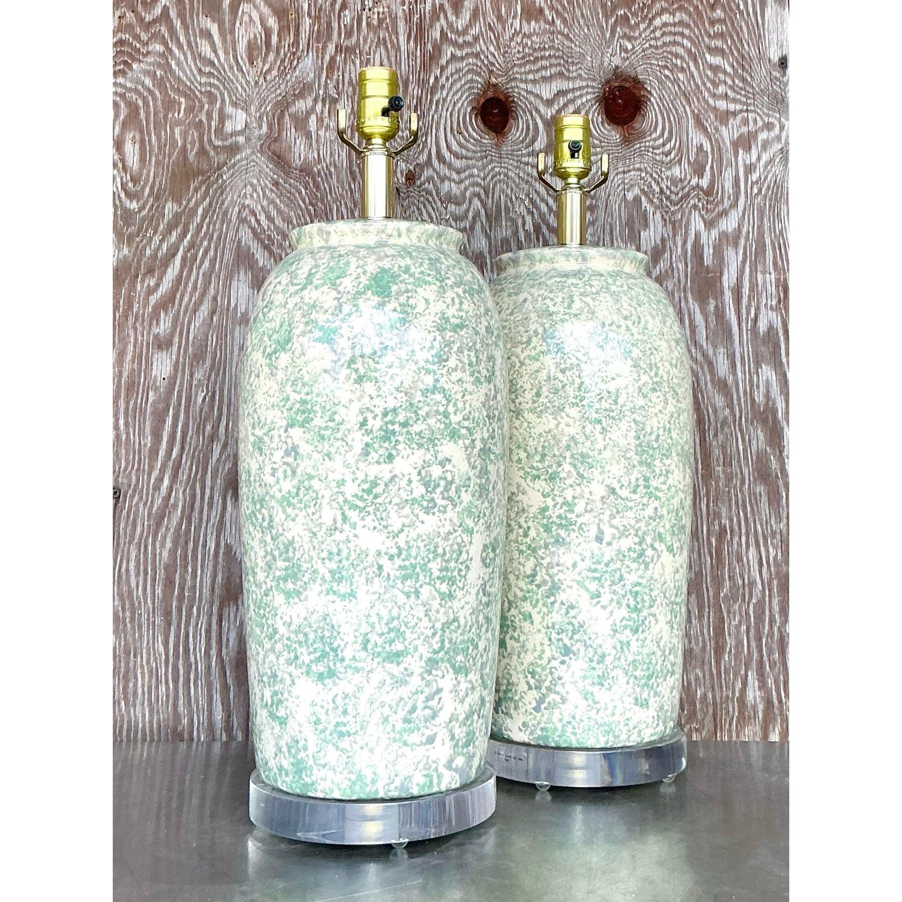 Dieses atemberaubende Paar Vintage-Keramik-Tischlampen strahlt mit seiner zartgrünen und cremefarbenen Glasur, die an handgefertigte Bauer-Keramik erinnert, zeitlose Eleganz aus. Die weiche, abgerundete Silhouette wird durch klare Acrylböden