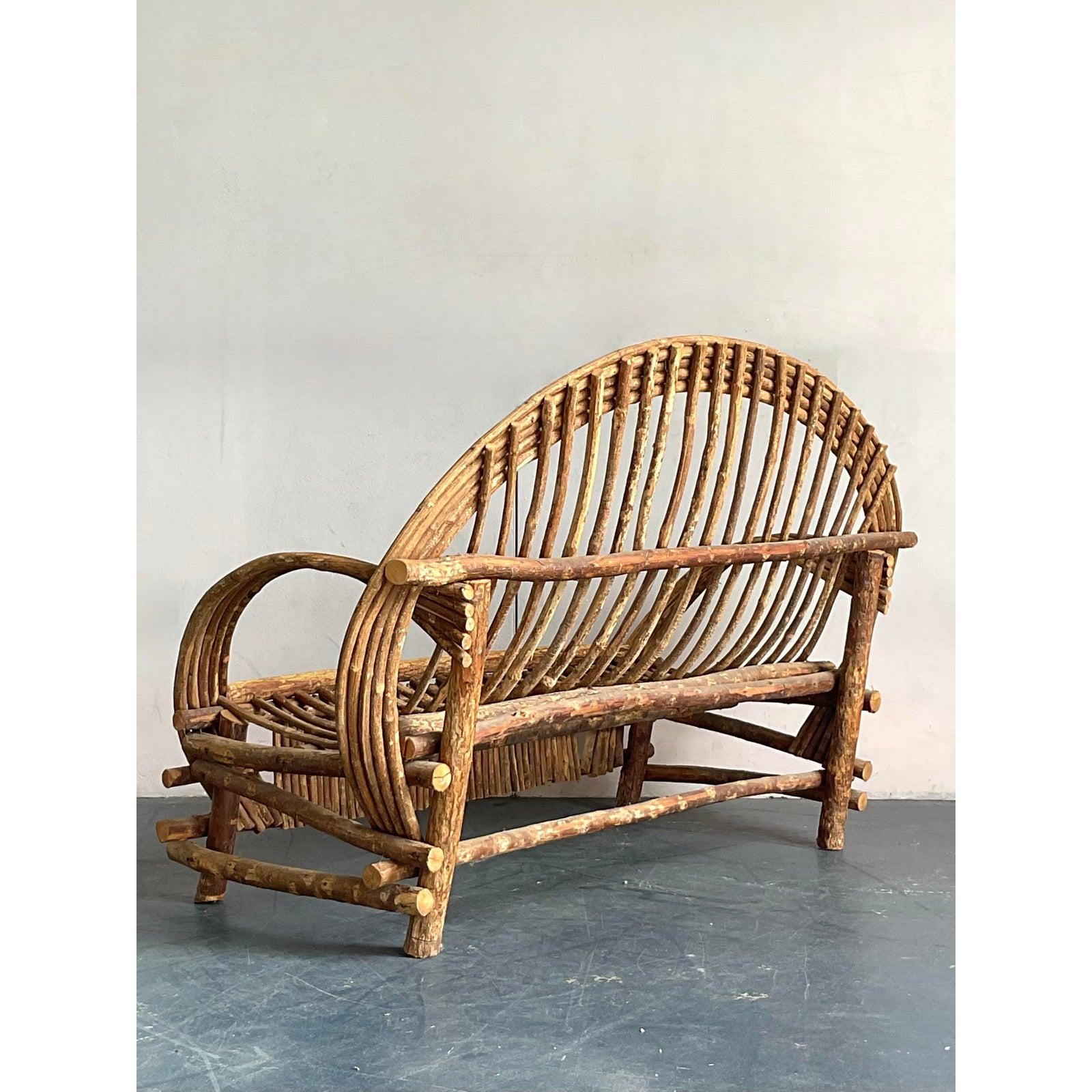 Embrace laid-back luxury with this charming vintage Boho Bent Branch Adirondack Sofa, a unique loveseat crafted from beautifully aged rattan and woven elements. This piece captures the essence of relaxed, natural living with its organic form and