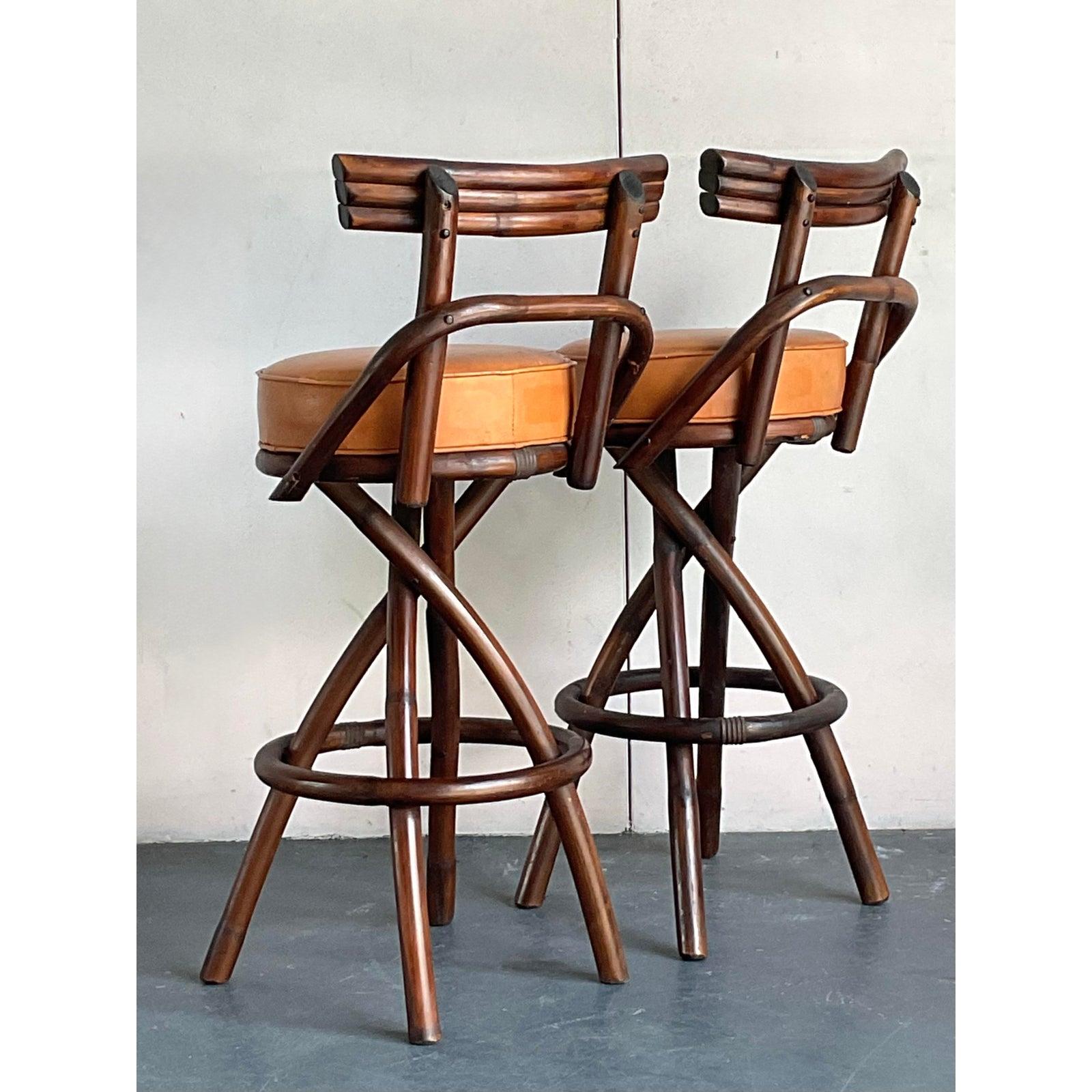 Elevate your kitchen island or home bar with this exceptional pair of vintage bar stools, showcasing the artful design of bent rattan paired with warm cognac leather seats. These stools embody a sophisticated bohemian aesthetic, blending natural
