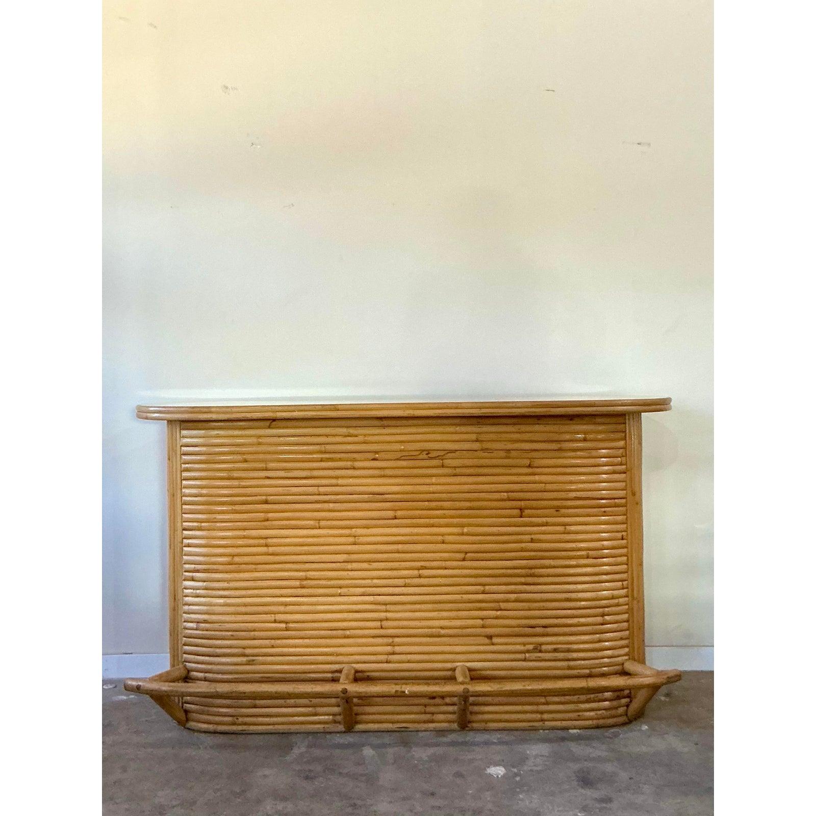 Diese herrliche Vintage-Bar verkörpert meisterhaft die entspannte Eleganz des Küsten- und Boho-Chic-Designs der 1970er Jahre. Die geschwungene, kurvenreiche Form wird aus Hunderten von einzeln gedämpften und gebogenen Rattanrohren gefertigt, die eng